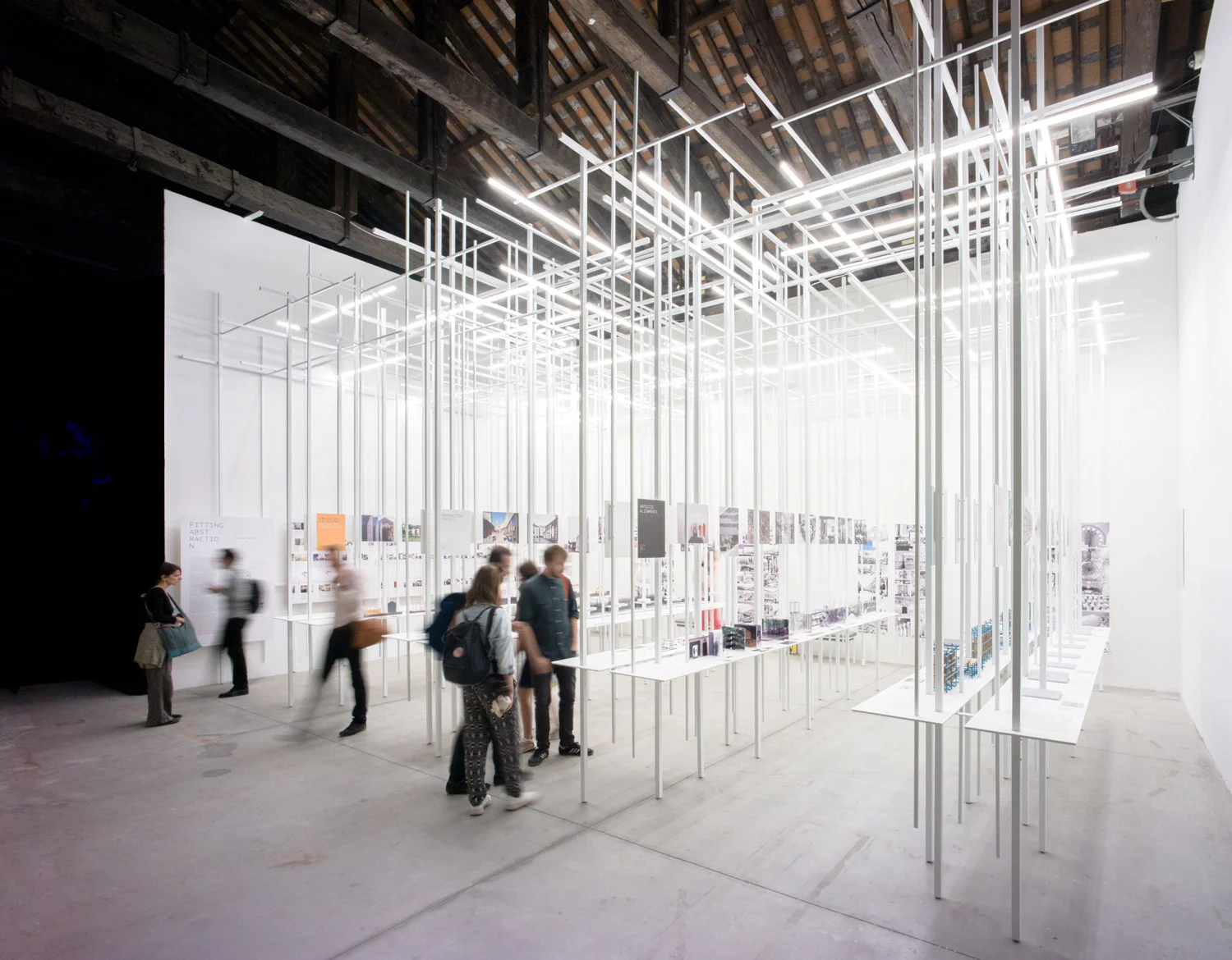 Fitting Abstraction is an installation that converges the atmospheric and the documentary. It is a plug-and-play analog interface powered by information proper. The installation explores the potentials of the exhibition medium to not only convey a scholarly argument but also to become a tool of research. The installation spatializes eight fundamental architectural values engendered through a tacit hybridization of modernist principles with locally existing social and architectural substrates and displays them as eight spatial conceptual diagrams. Set perpendicularly to the main corridor, they stretch parallel to each other filling the space’s entire depth, while chronologically spanning the whole addressed century. Thus, FA converges chronology with space to create a thematic-temporal grid that materializes the installation’s very argument. To do so, the installation merges the scaffold and the exhibits into an indivisible whole. In that sense, it belongs to a line of modernist tradition epitomized in the Yugoslav Pavilion at the XIII Milan Triennial from 1964, designed by Vjenceslav Richter. White powder-coated steel bars are the only structural element used repeatedly throughout the installation, serving both as vertical and horizontal structural members. They carry exhibition materials, both acrylic sheets and spatial conceptual diagrams, and calibrate their display to coordinate the entire disposition. The installation is entirely self-sufficient, with integrated LED lighting system; it comes as a kit of parts that is completely demountable and can be easily reassembled.