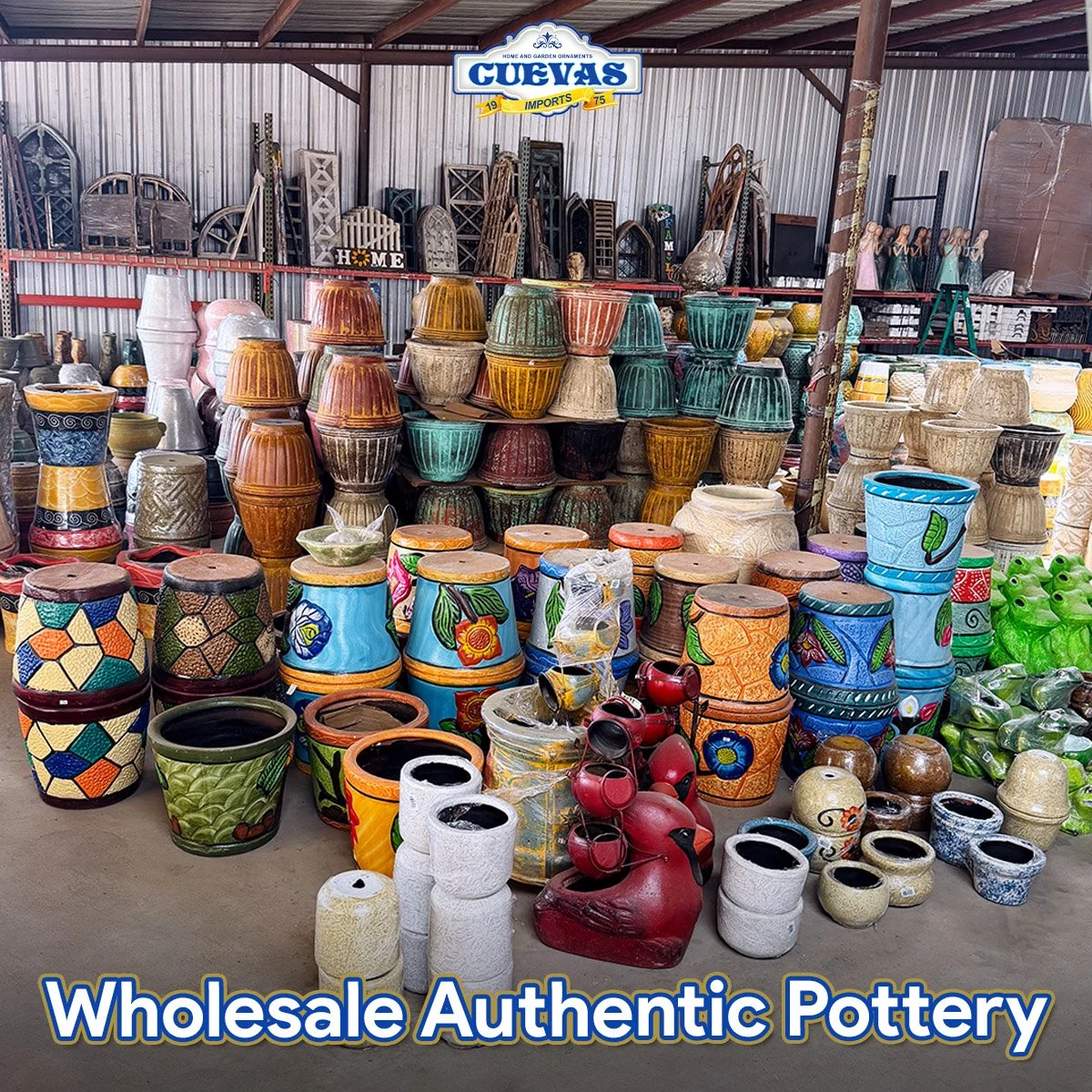A display of colorful wholesale pottery, including painted flower pots and decorative vases, arranged on shelves and the floor inside a warehouse with metal walls and ceiling. There are garden ornaments and decorative items on top shelves.