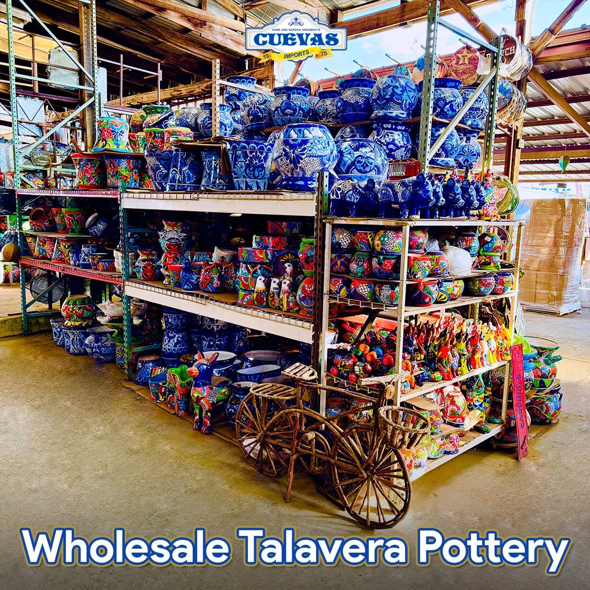 A display of colorful Talavera pottery including vases, bowls, and decorative items on metal shelves at a wholesale pottery store, with a sign that reads "Cuevas Imports" and a small wooden cart in front.