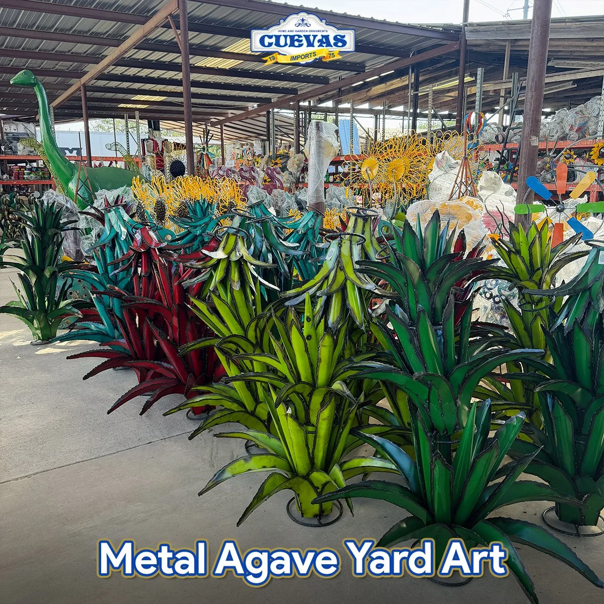 Colorful metal agave yard art sculptures shaped like agave plants in green, red, and teal, displayed outdoors at a store with a sign that reads "Cuevas".