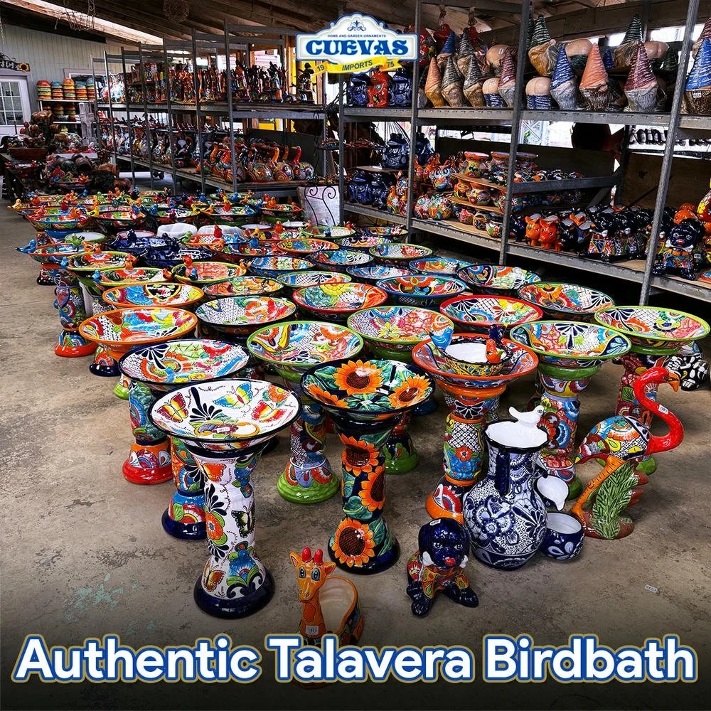 Colorful Talavera-style birdbaths with decorative animal figurines, displayed in a store with shelves of similar ceramics in the background.