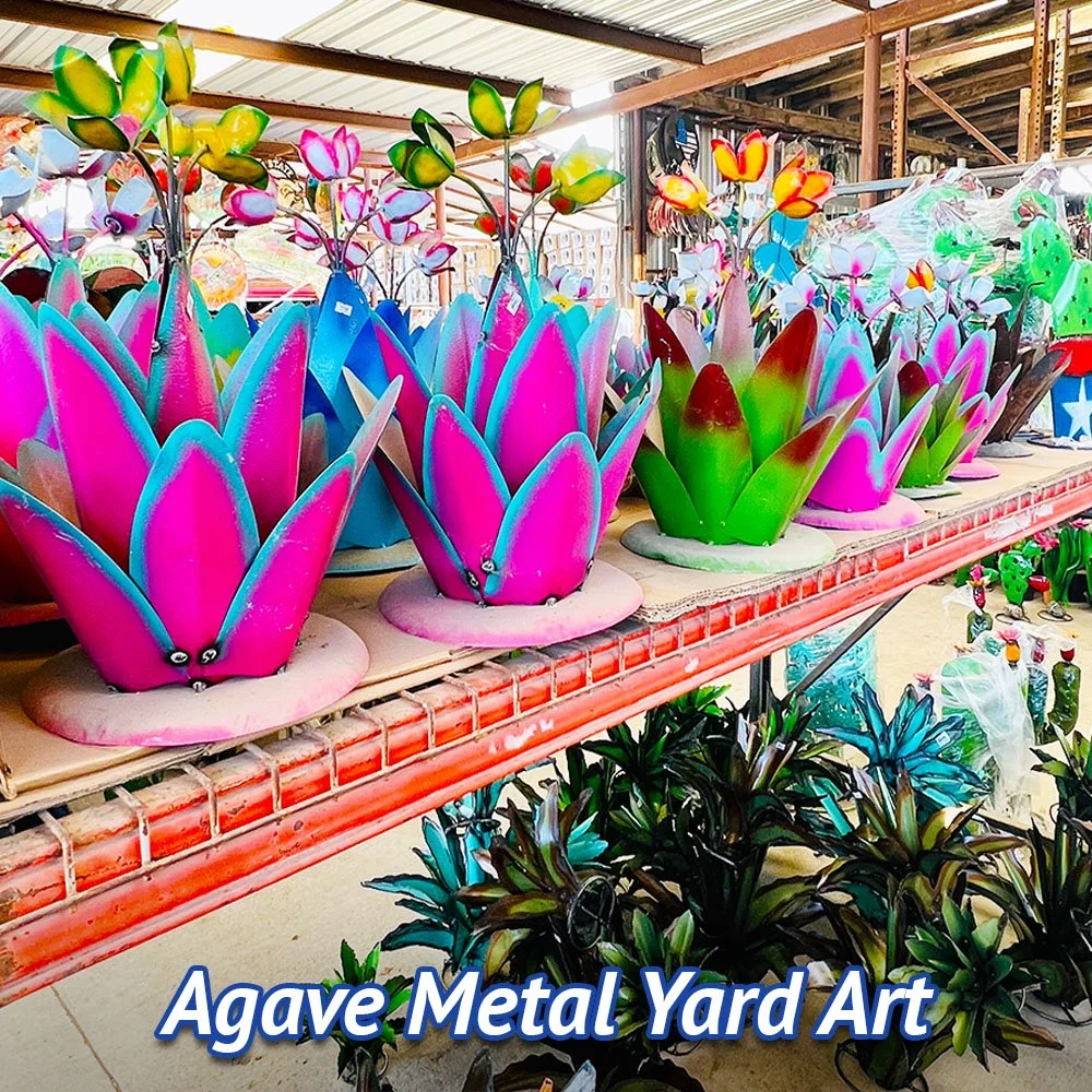 Colorful metal yard art sculptures resembling succulents and cacti, displayed on outdoor shelves at a store.