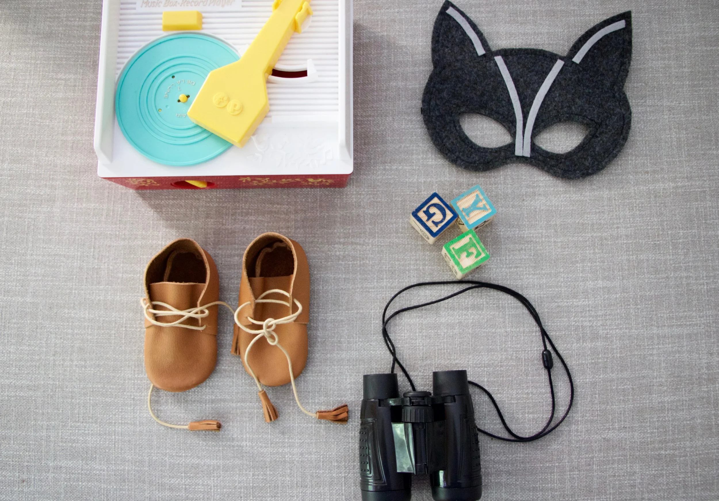Toy record player: Fisher-Price Classics, Scout Moccs: Little Pine Outfitters , Mask: Mahalo , Toy Blocks: Target, Toy Binoculars: Amazon