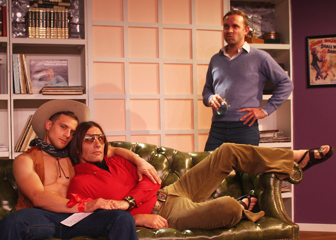 Cowboy (Ryan Wingert) and Harold (Ryan Landry) cuddle on the couch as Michael (Victor Shopov) looks on in Zeitgeist Stage Company's The Boys in the band (Photo Credit: Richard Hall/Silverline images). 
