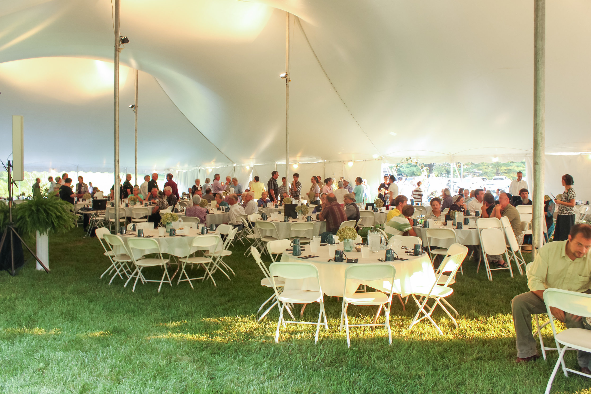 White folding chairs and round tables for your tent wedding reception 