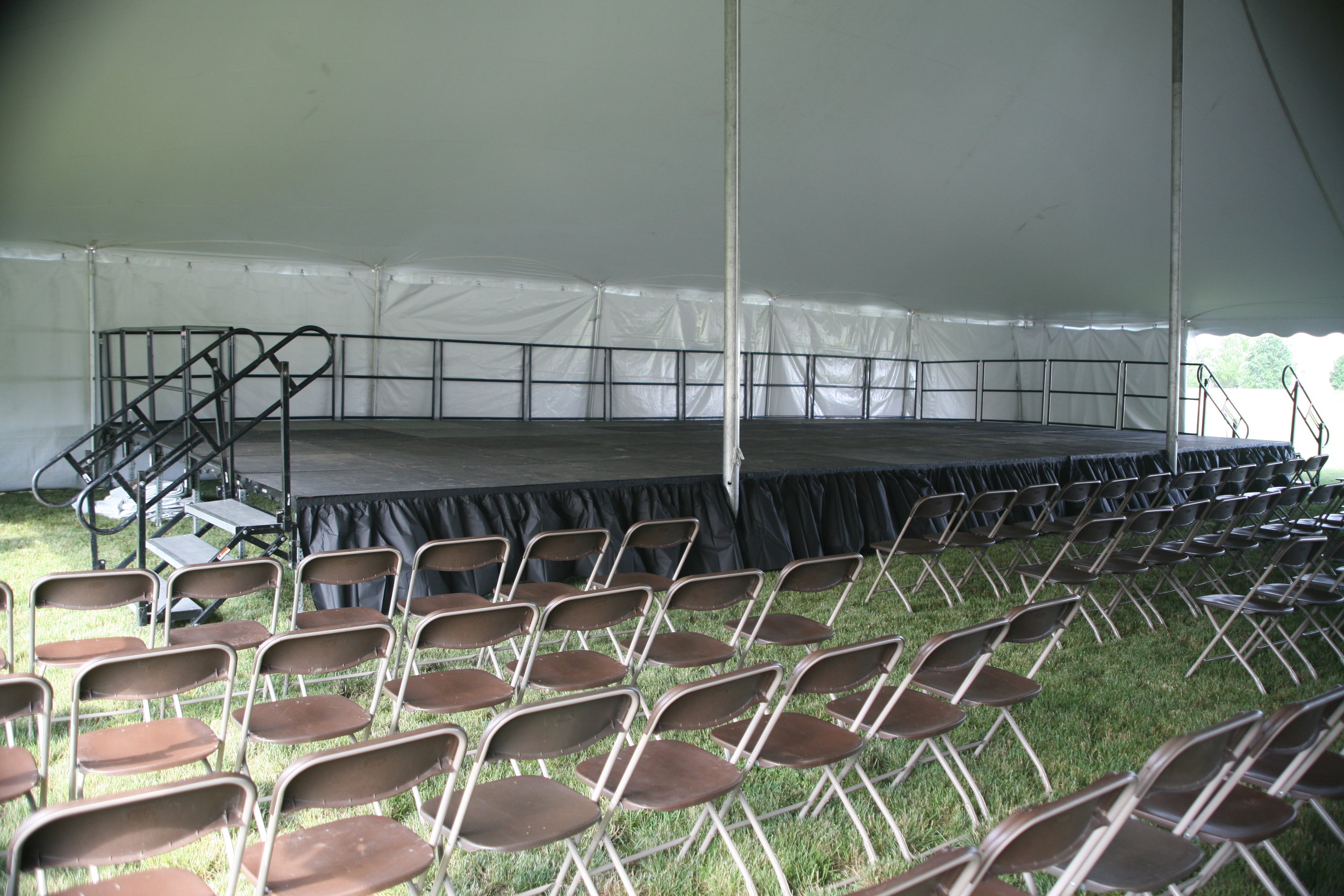 Brown folding chairs and a stage to rent for your tent event