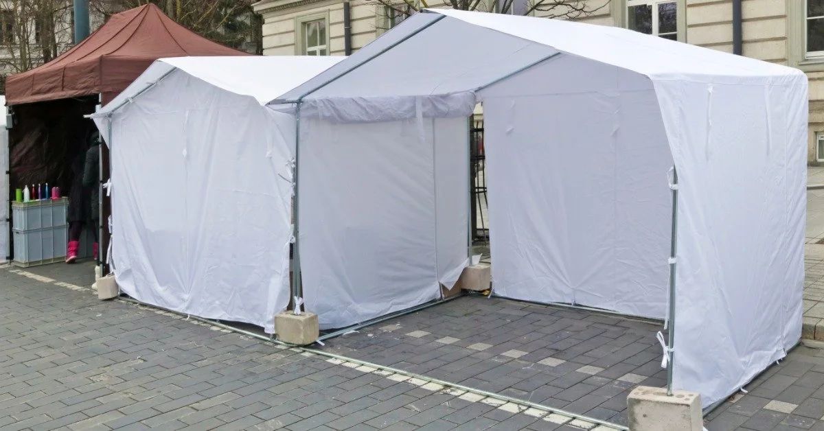 Three small event tents installed next to each other outside. Two tents are white and the other is brown.