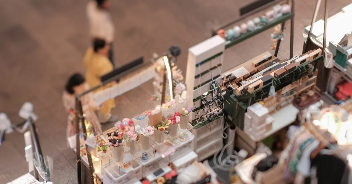 An outdoor pop-up retail shop full of clothing, jewelry, and accessories that is overlooking a walkway.