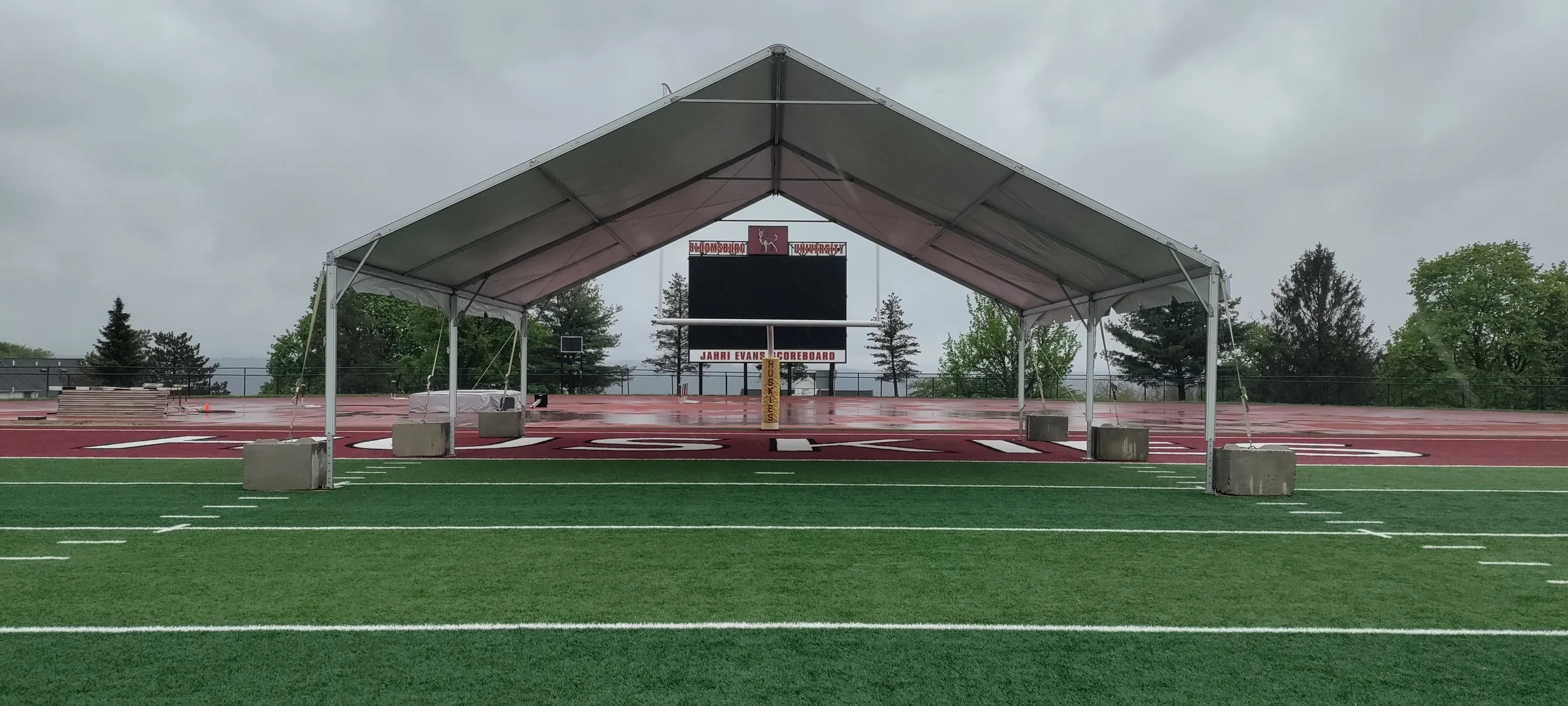Frame tent on astroturf football field secured with concrete weights