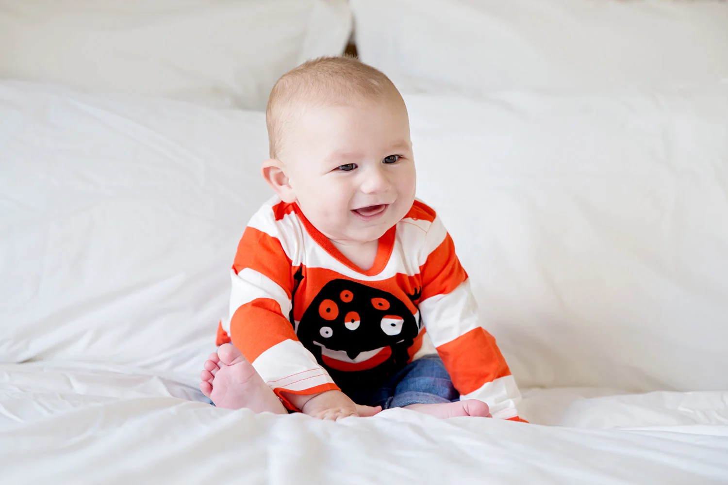 Baby pictures - 8 month old Harry on a big bed in a Halloween t-shirt