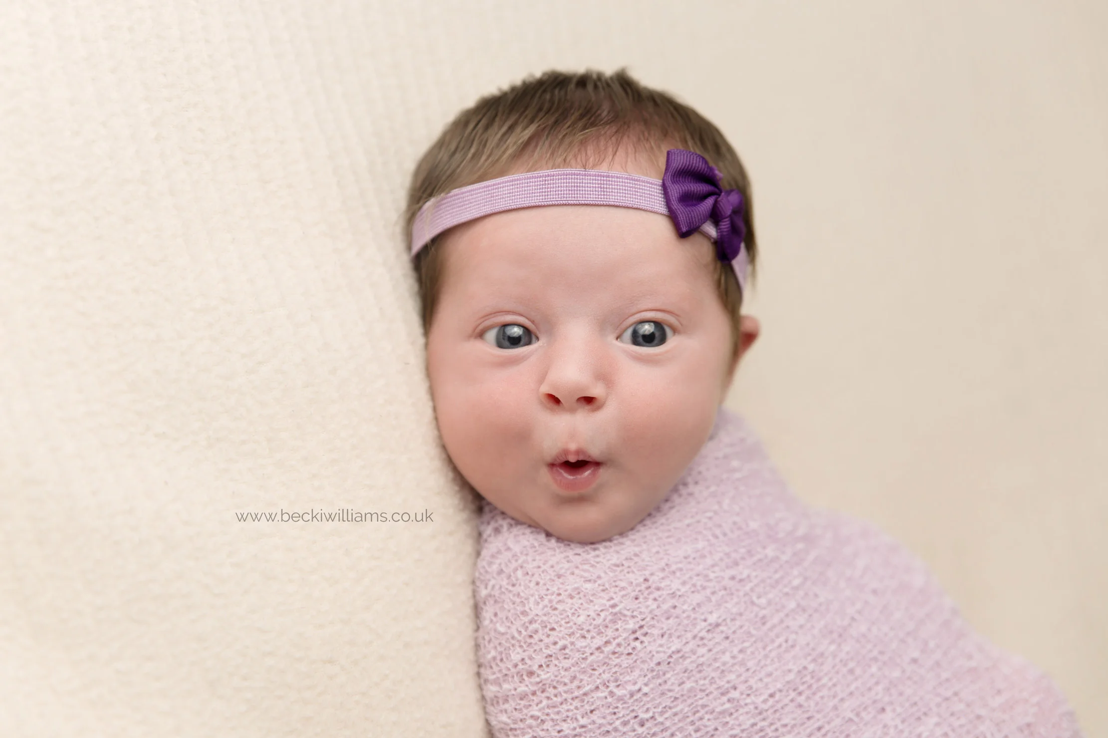 Newborn pulls funny face during her newborn baby photo shoot in Hemel Hempstead