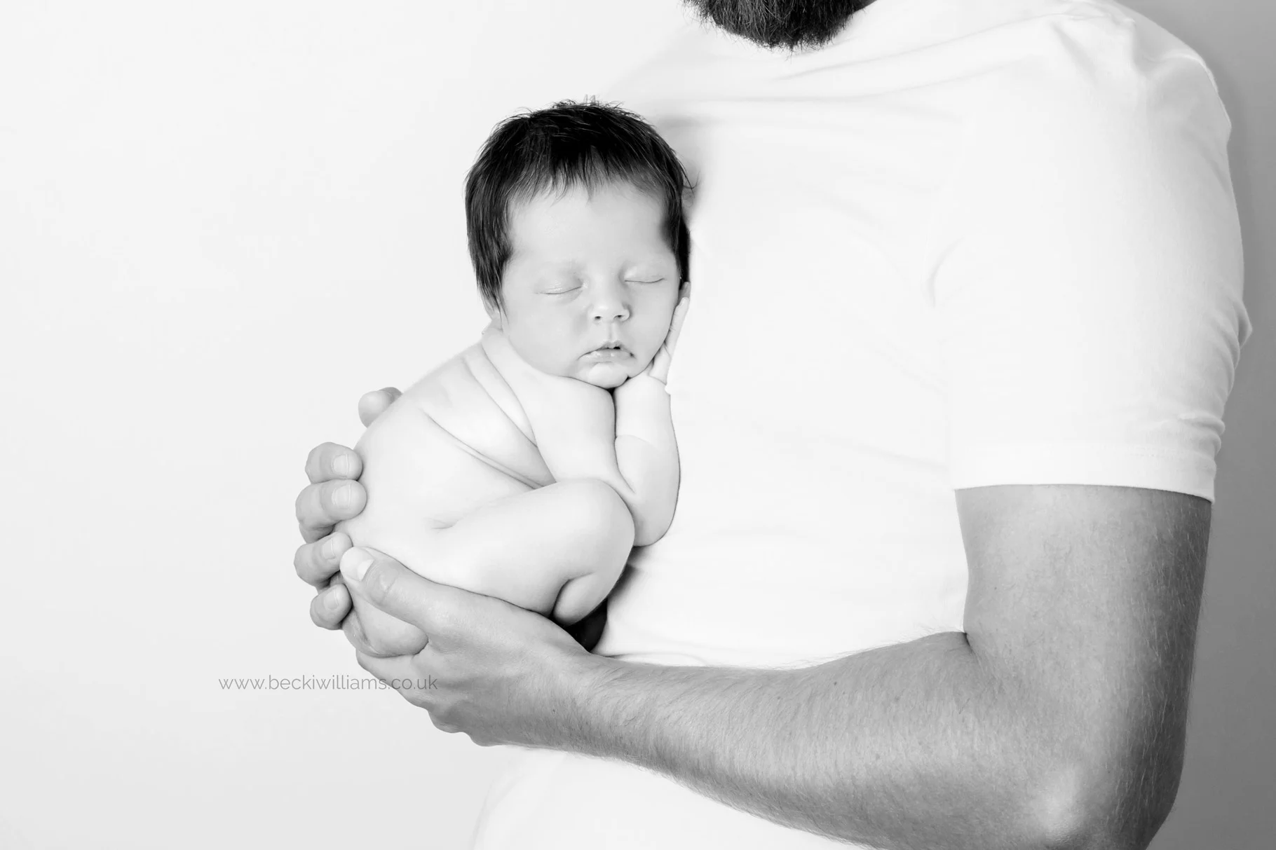 Newborn girl fits perfectly in her daddy's hands asleep