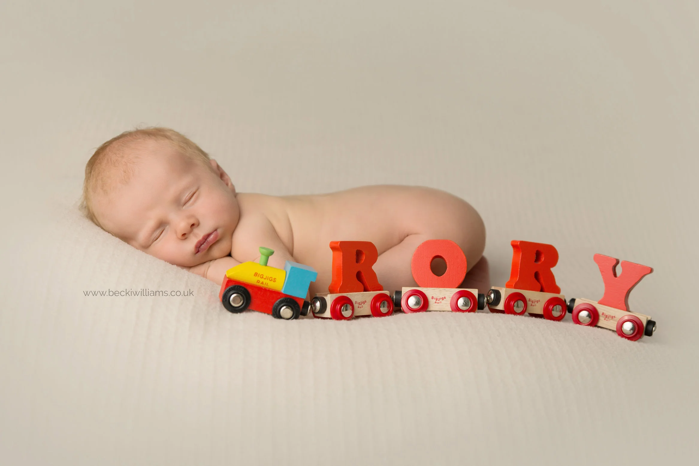 newborn baby rory with his toy train at his newborn photo shoot in hemel hempstead