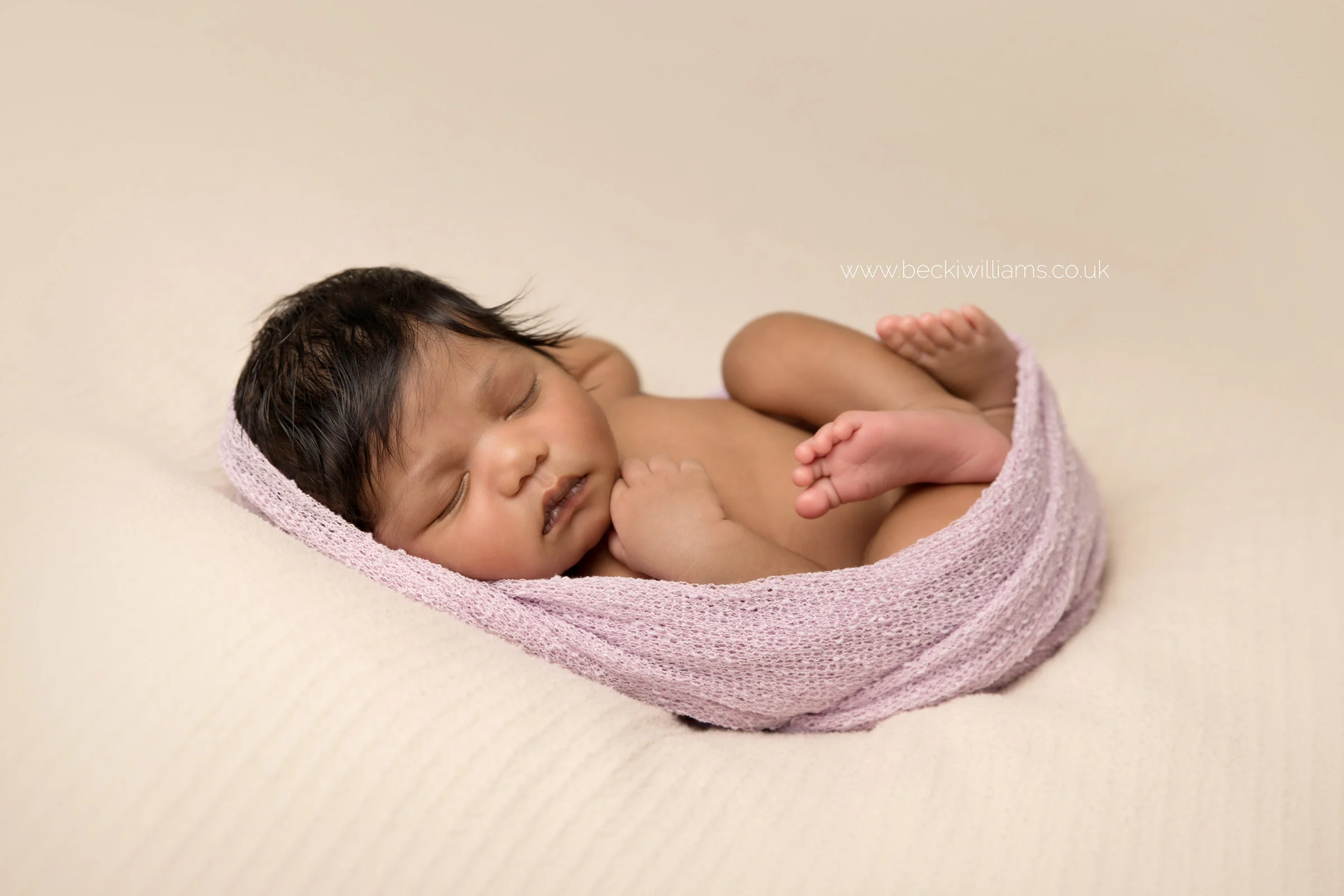 newborn baby girl laying on her back for her newborn photo shoot in hemel hempstead in black and white