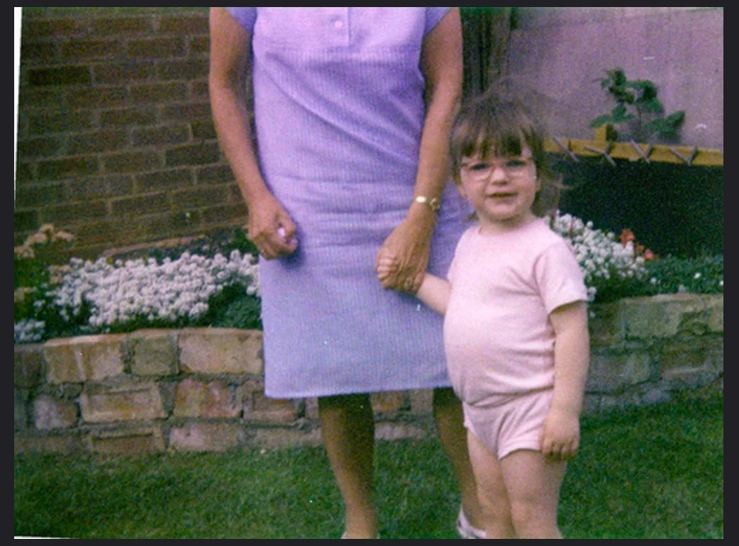 young toddler in the 80s, standing with her nan in the garden