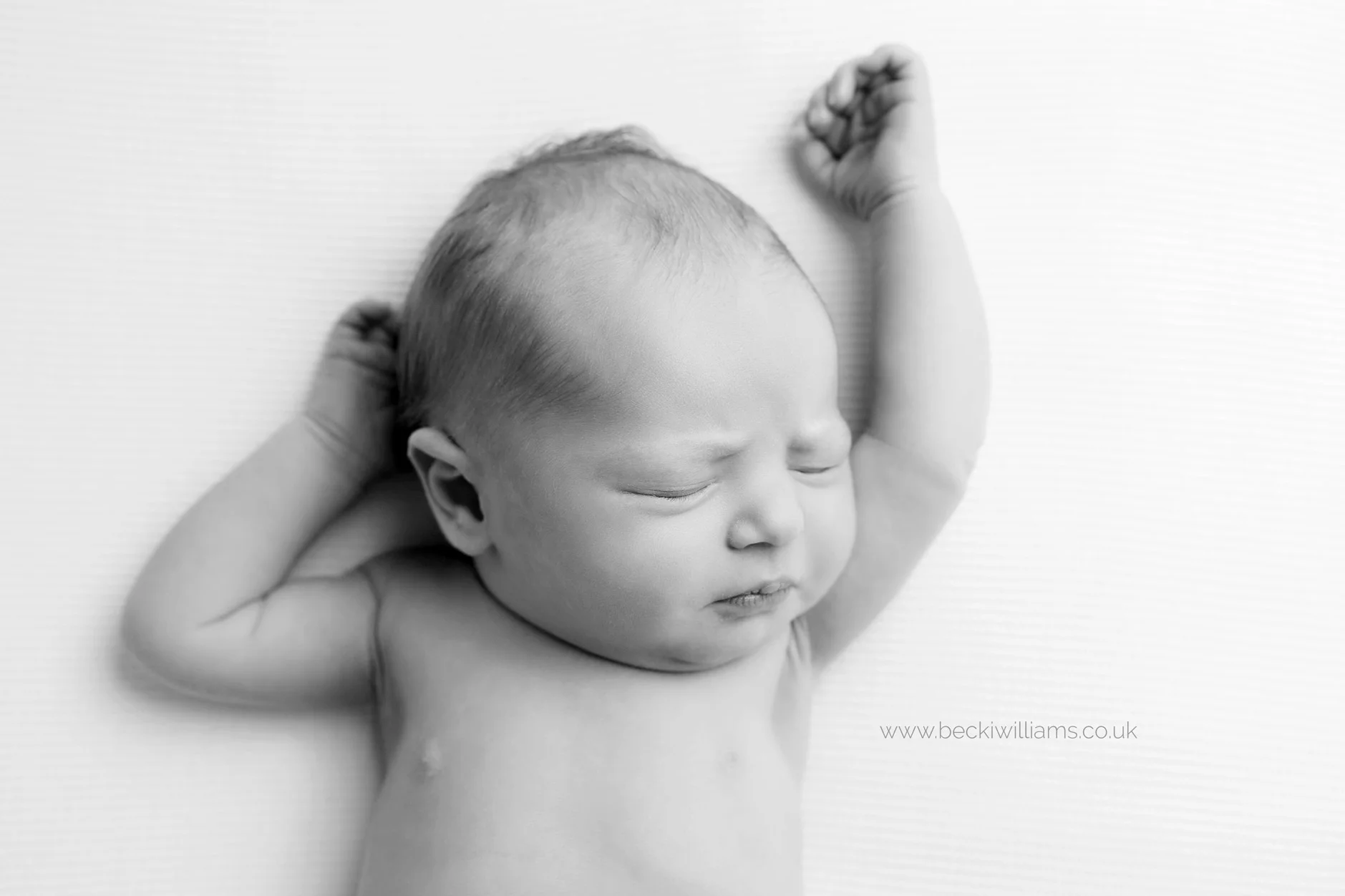newborn baby stretching in black and white
