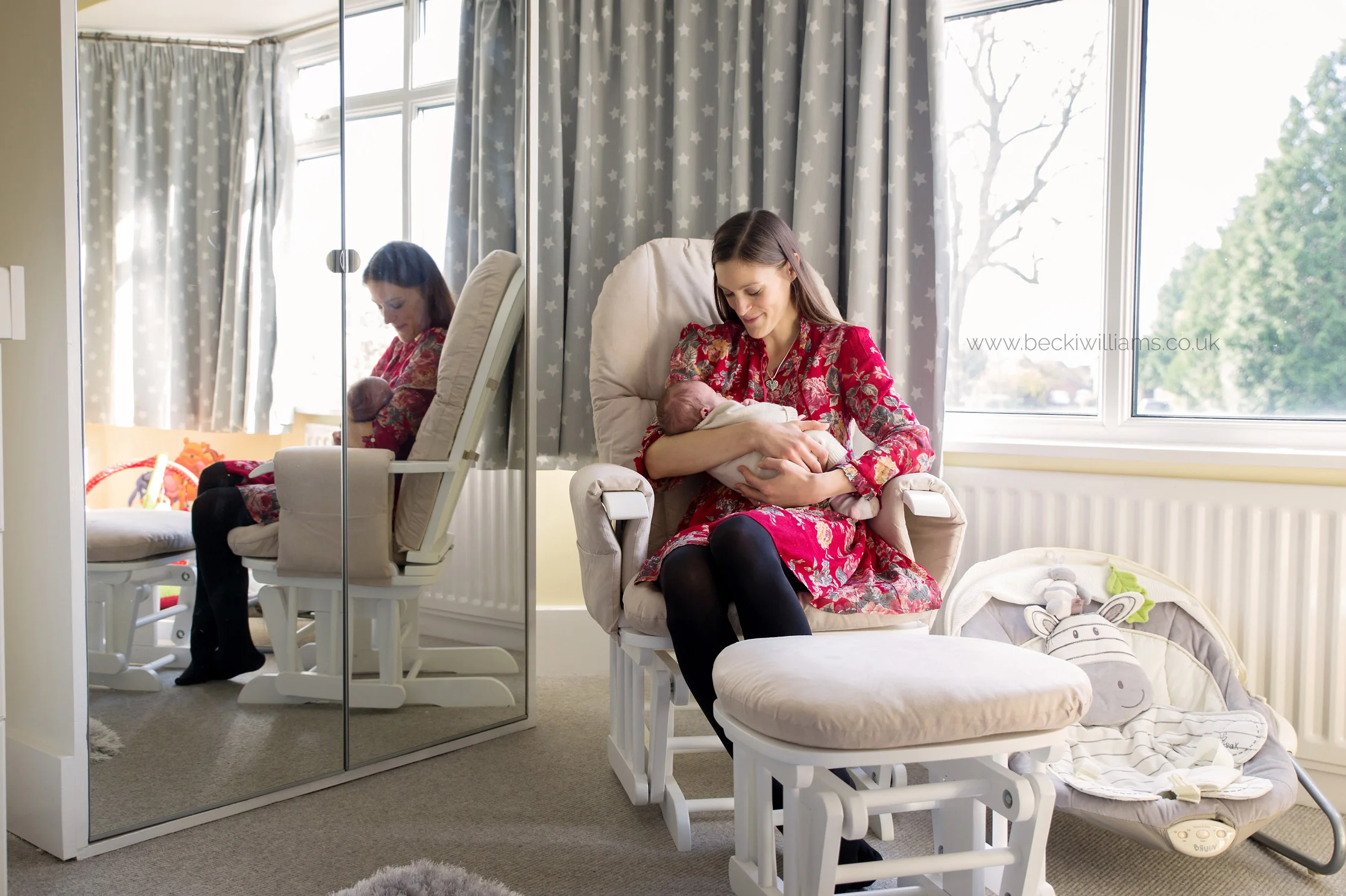 new mum sitting her newborn baby girl's neutral nursery on a rocking chair, holding her baby