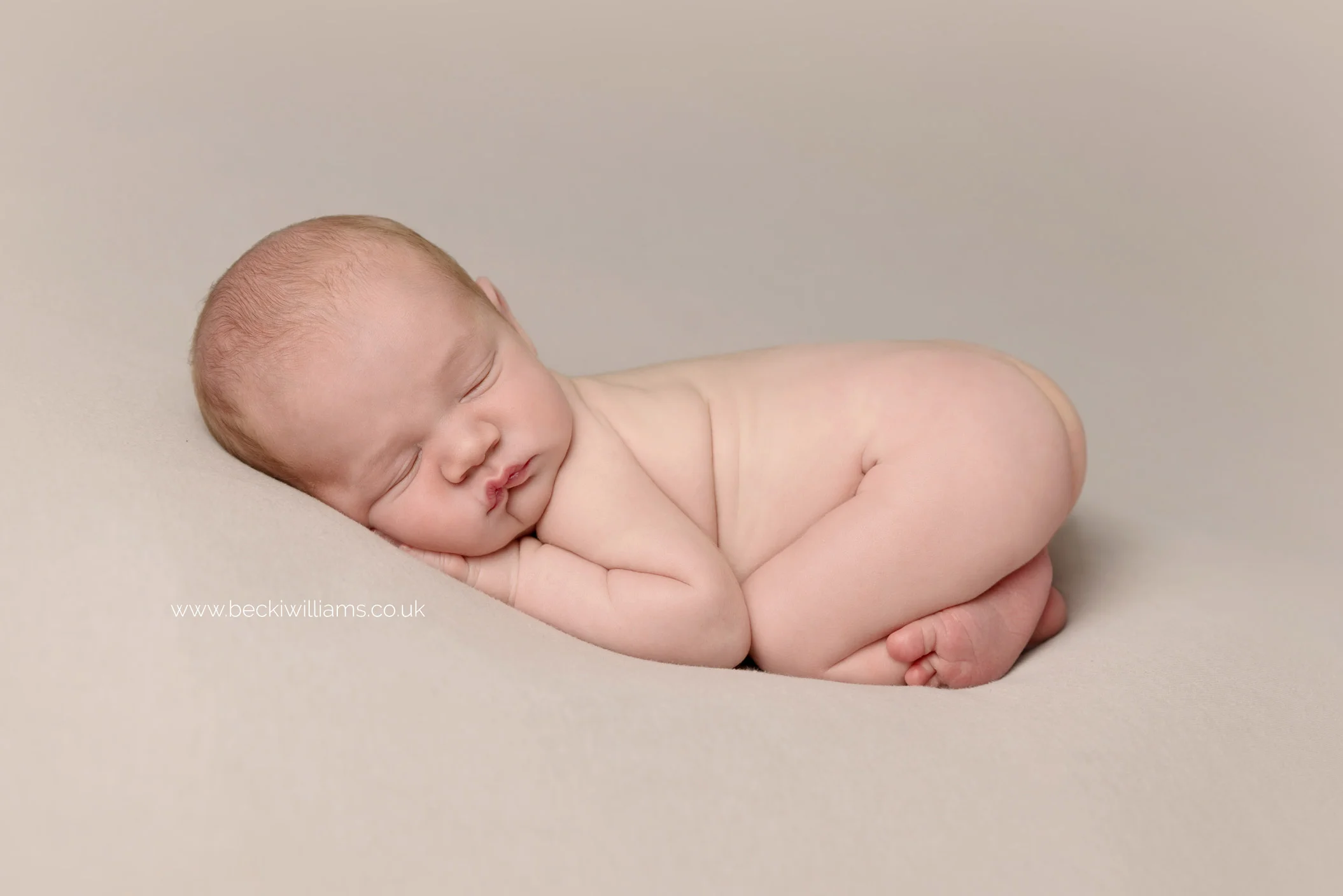 newborn baby boy sleeping on his tummy on a grey blanket