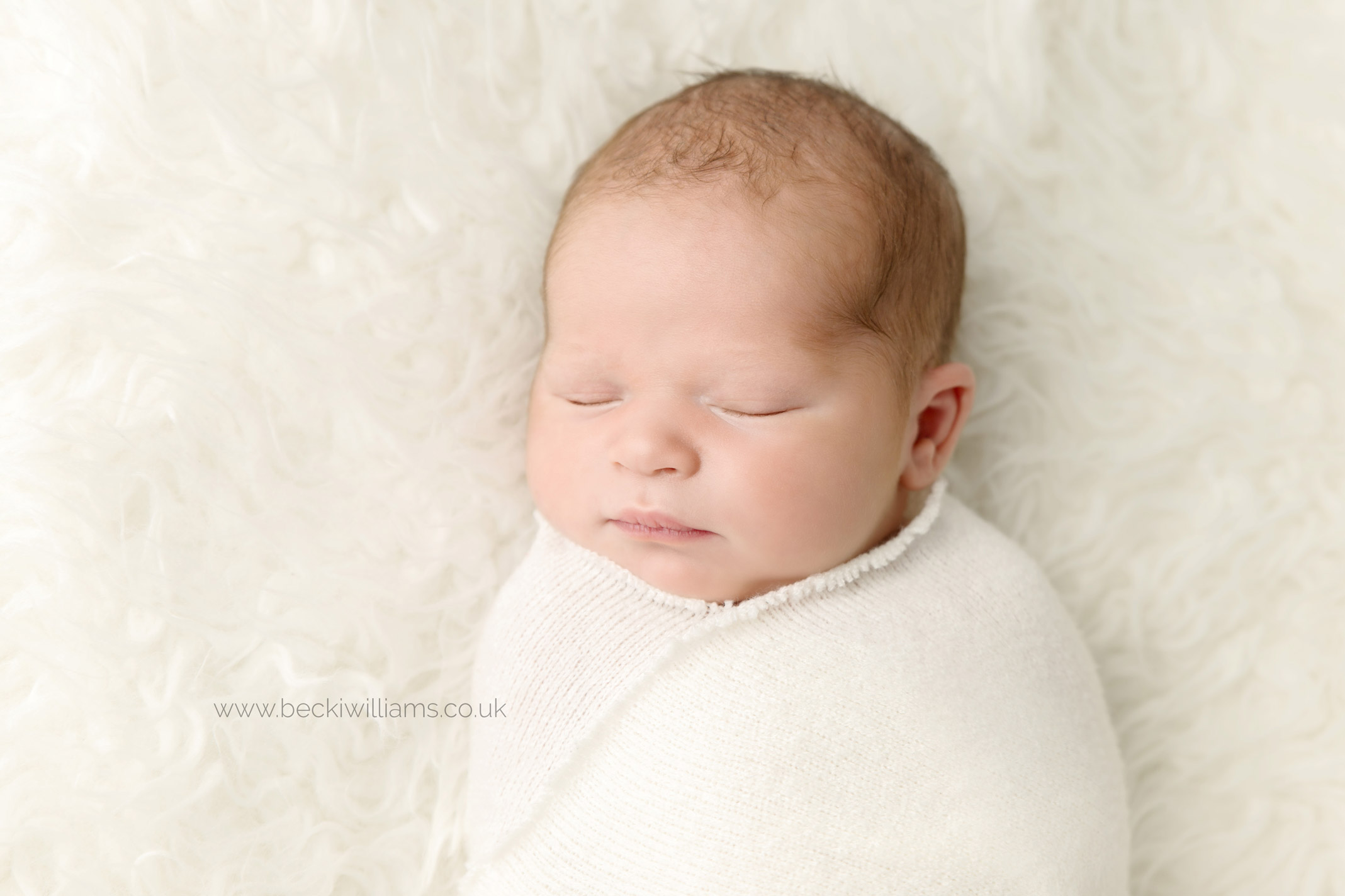 Natural newborn photo of baby boy wrapped in a cream blanket