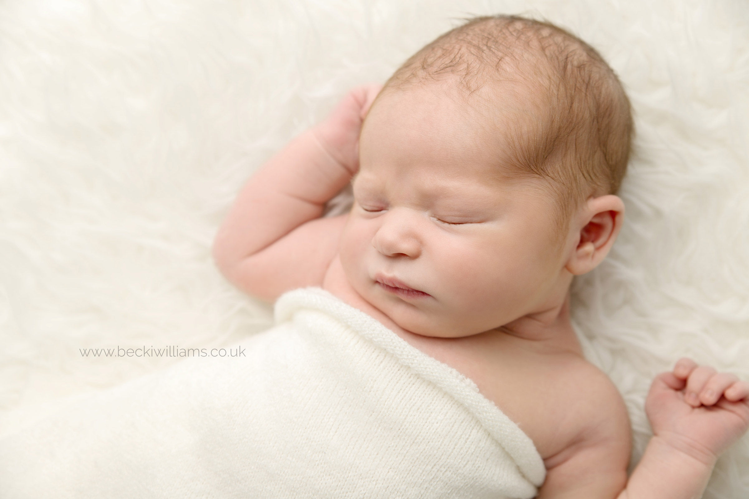 Natural newborn photo of baby boy wrapped in a cream blanket