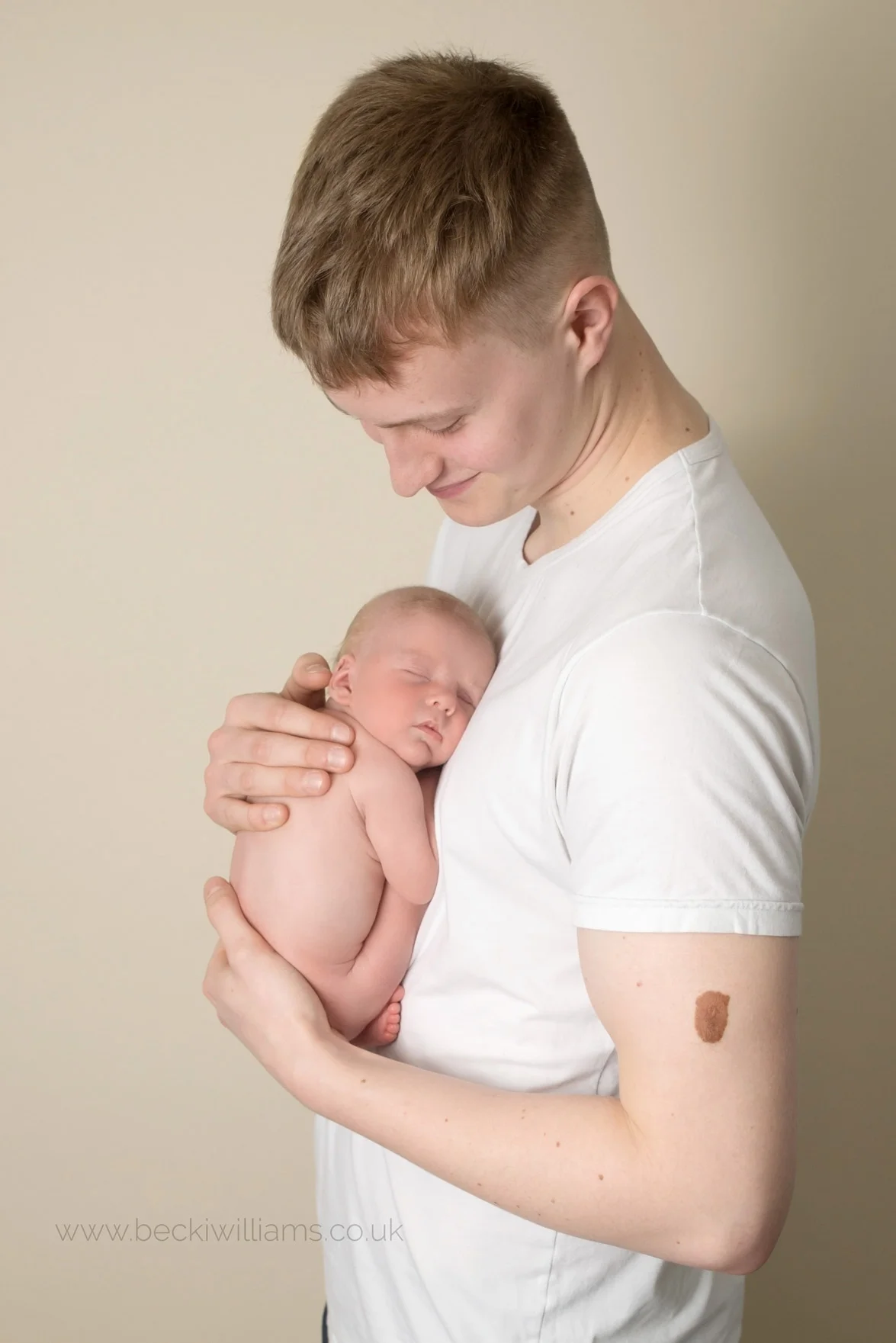new dad holding his newborn baby boy at their newborn photo shoot in hemel hempstead