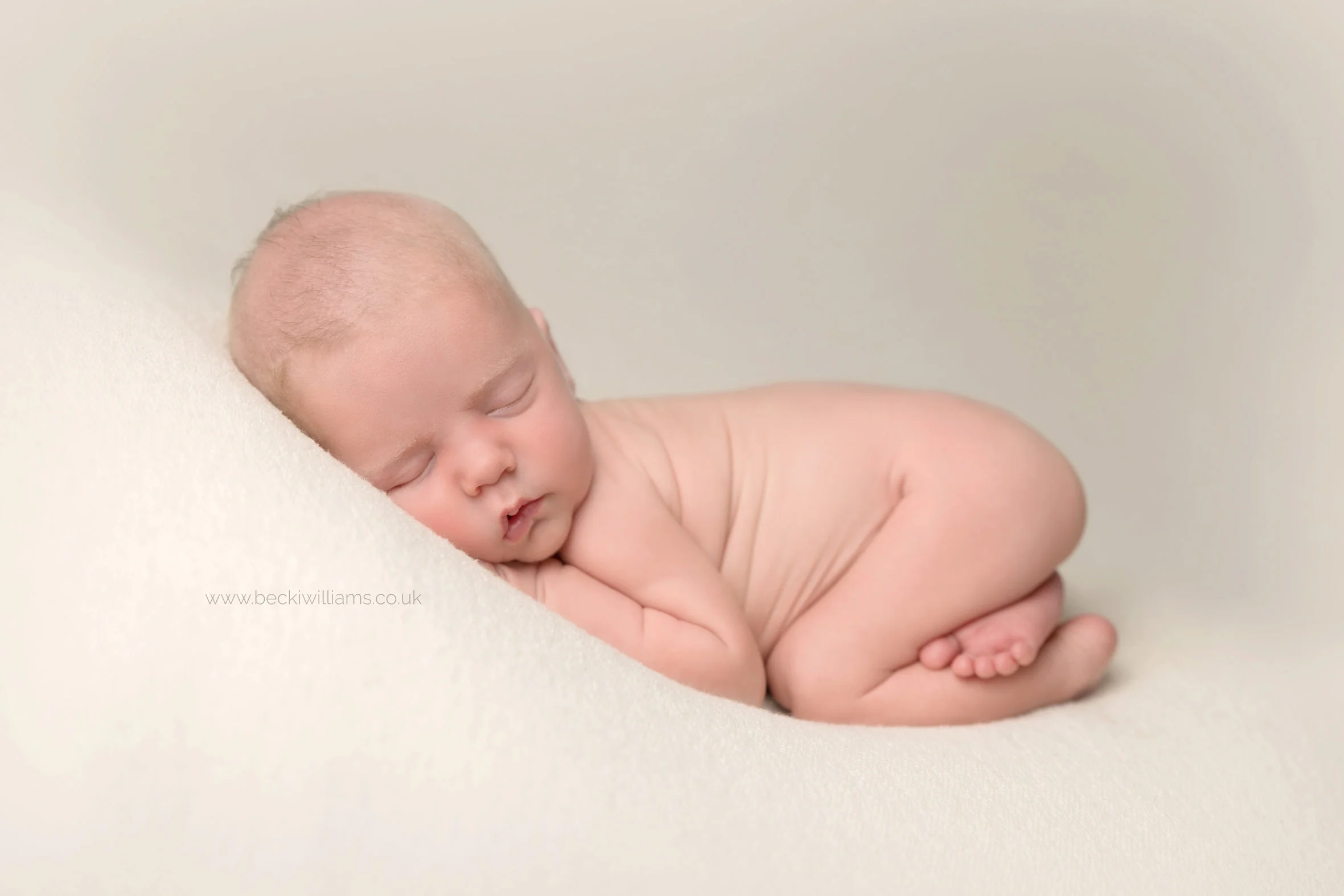 newborn baby boy laying on his tummy in a 'bum up' pose for his newborn photo shoot in hemel hempstead