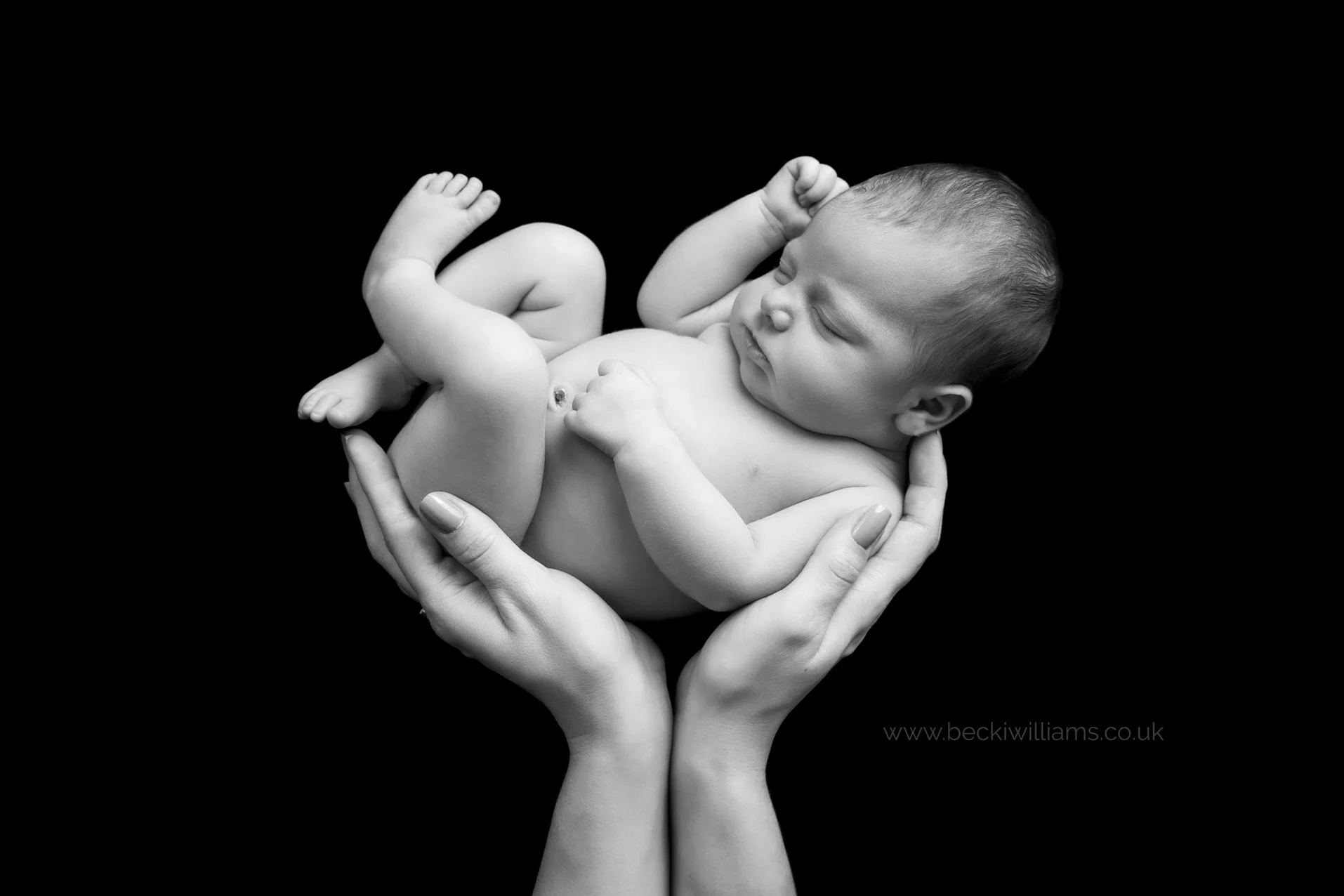 black and white image of newborn baby in her mother's hands at her newborn photo shoot
