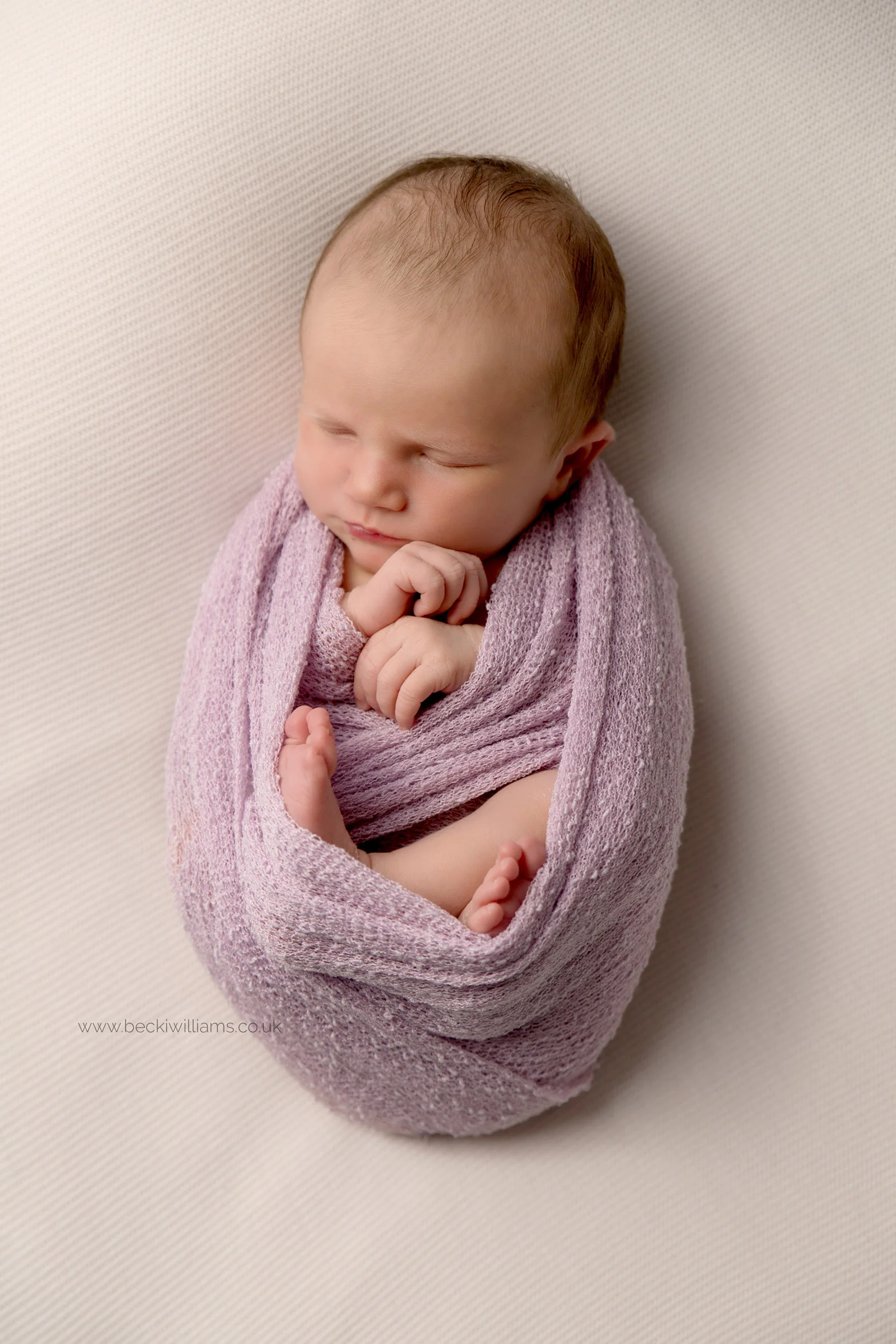 newborn baby girl wrapped in a pink wrap for her newborn photo shoot in Hemel hempstead