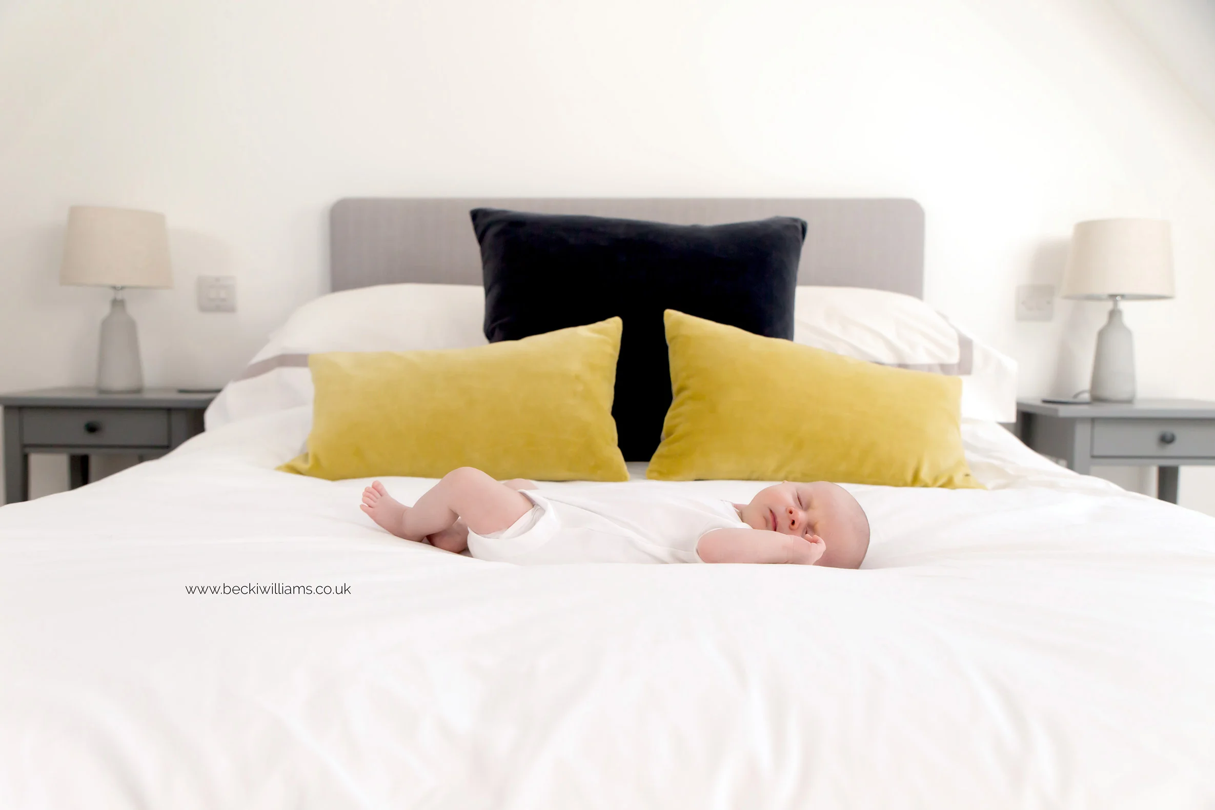 newborn baby girl laying on her parents bed for her newborn photo shoot in st albans