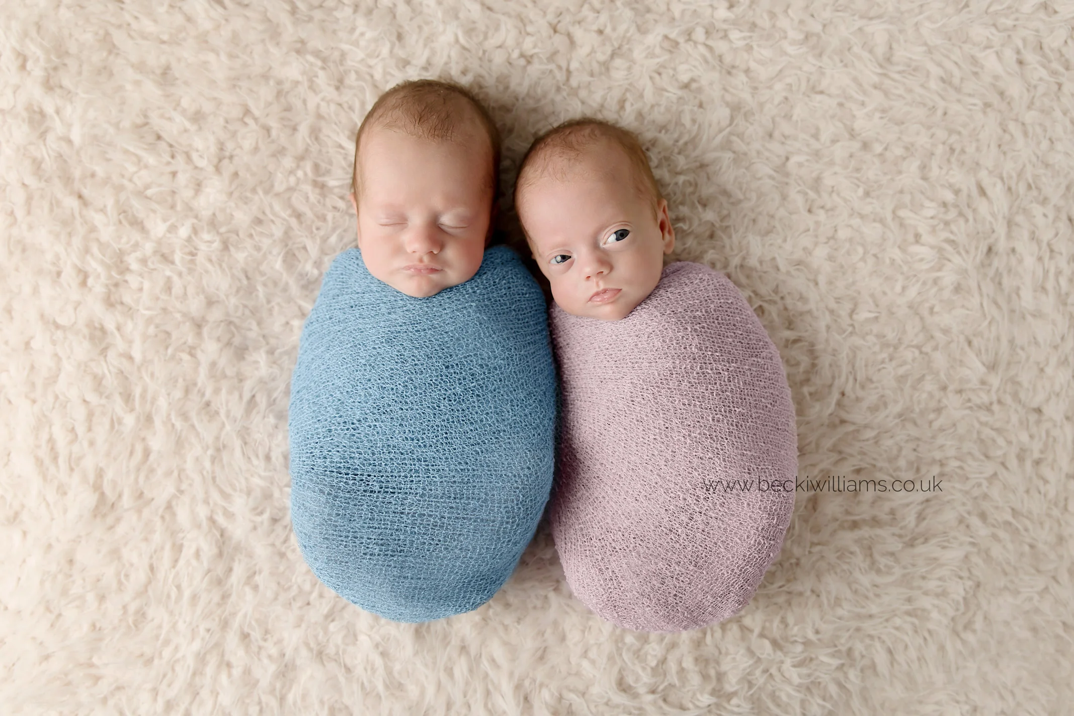 newborn twins wrapped in pink and blue at their newborn photo shoot in Hemel hempstead