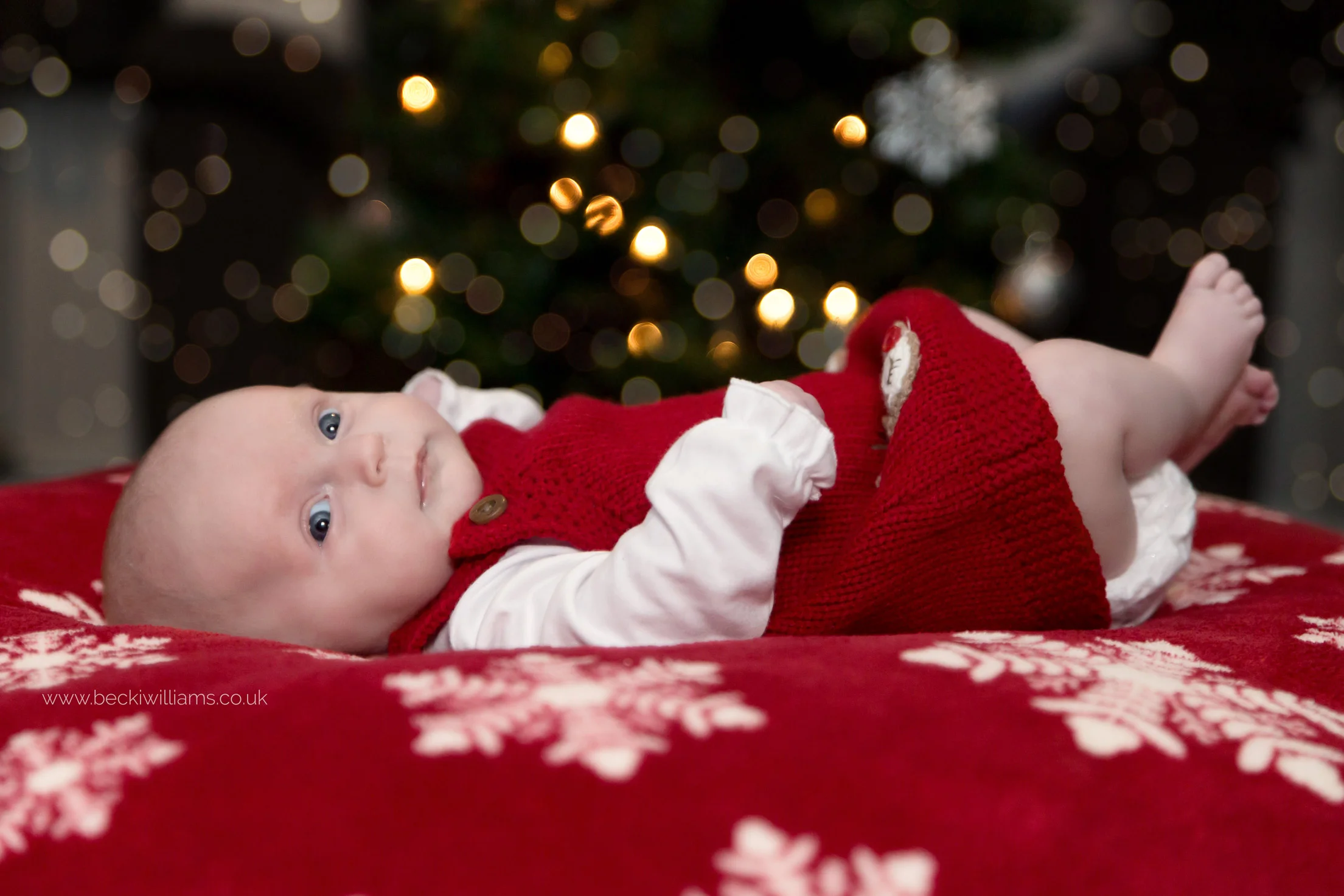 2 month old baby in front of a christmas tree