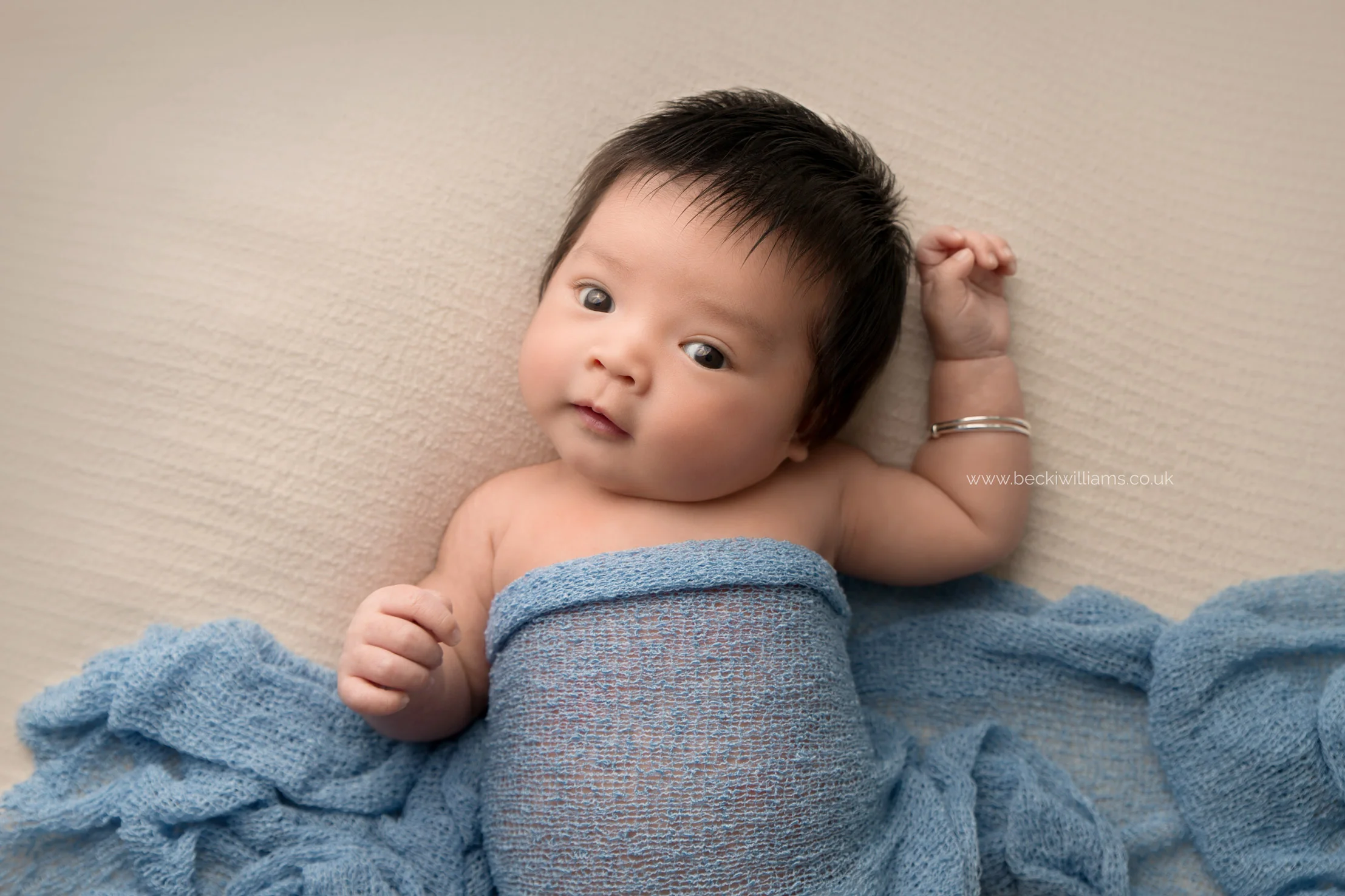 newborn boy covered in a blue blanket at his newborn photo shoot in hertfordshire