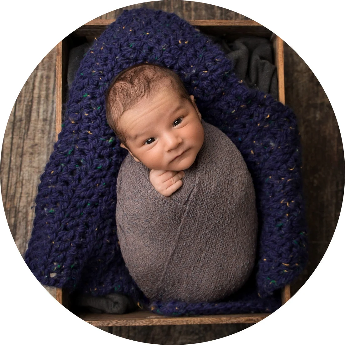 wrapped, newborn baby on a blue blanket in a crate