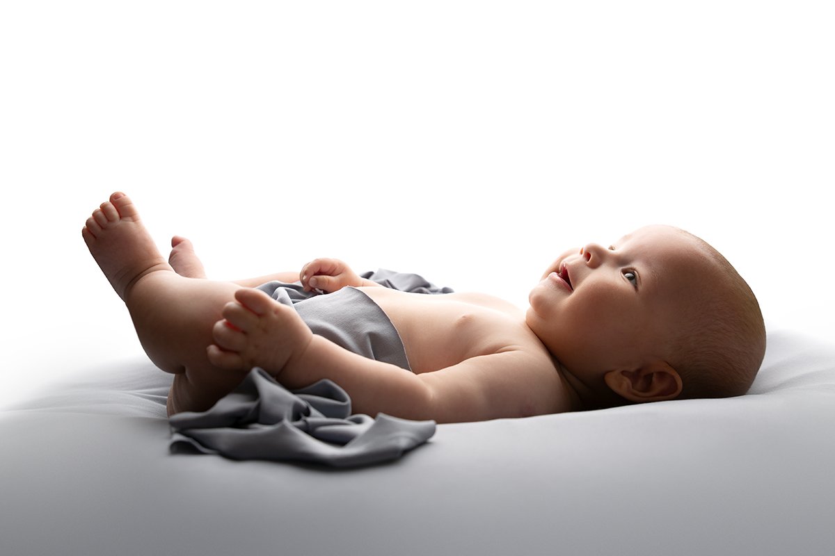 4 month old baby boy lays on a blue blanket at his professional photo shoot