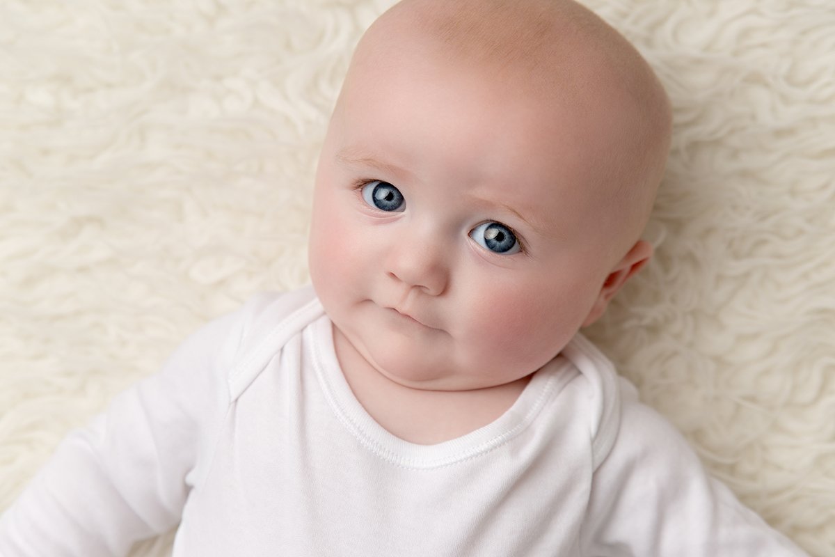 Close up photo of a baby's face as she stares up at the camera at her baby photo shoot in Milton Keynes