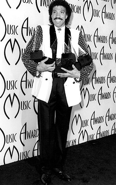 Lionel Richie in 1985 Lionel Richie, too, has his arms full at the 1985 AMAs.
