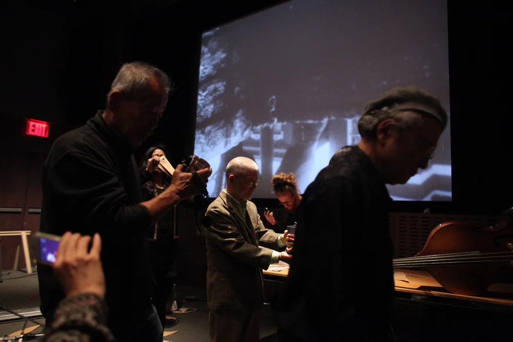  Performance of Kanesaka Kenji’s film,  Hop Scotch  (1967, 10:26min), in 2012 at MoMA, New York. From left to right: Unknown, Tone, Kulik, and Takahiko Iimura. Performed by Yasunao Tone, Sam Kulik, Matt Mottel, Lary 7, Miki Kaneda, and Ann Adachi, 20