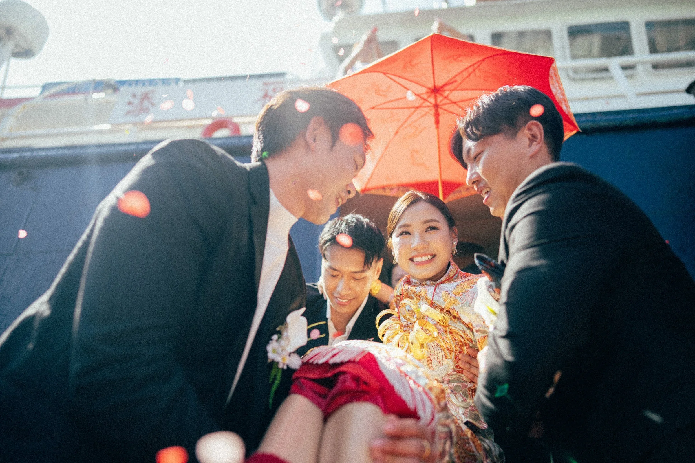 三聖水上人婚禮，Vanie在添福船側紅傘下微笑，Alex與親友在旁接應，逆光中可見飄落的紙碎
