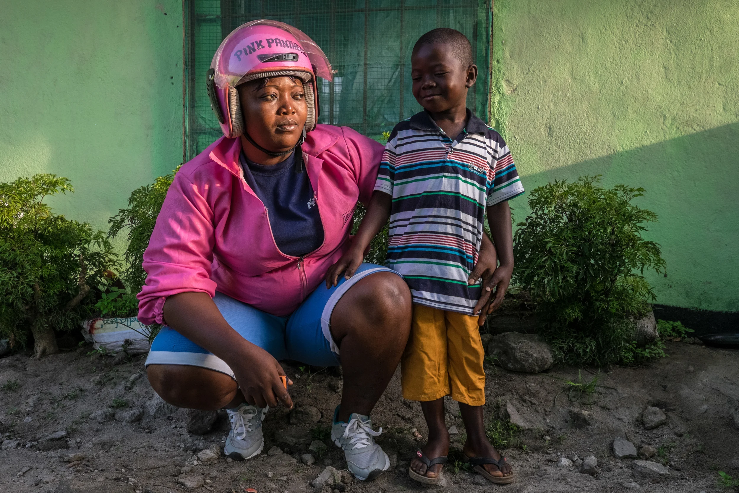 Dearest Coleman poses with her youngest son, at their home in Monrovia, Liberia on February 20, 2015. Dearest, a founding member of the Pink Panthers, works from 5 am to 9 pm most days. She uses a motorcycle that her boss lends her. Monday through Saturday the drivers must give nearly all of of their profits to the owners of the motorcycles, and then on Sunday the drivers can keep any profits they make. Dearest says her goal is to get her own bike one day.