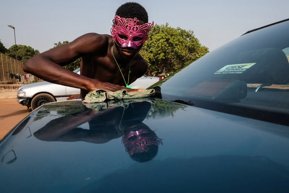 Bissau, Guinea-Bissau (February 6, 2016) - A man washes his car while wearing a Carnaval mask in Bissau, Guinea Bissau.