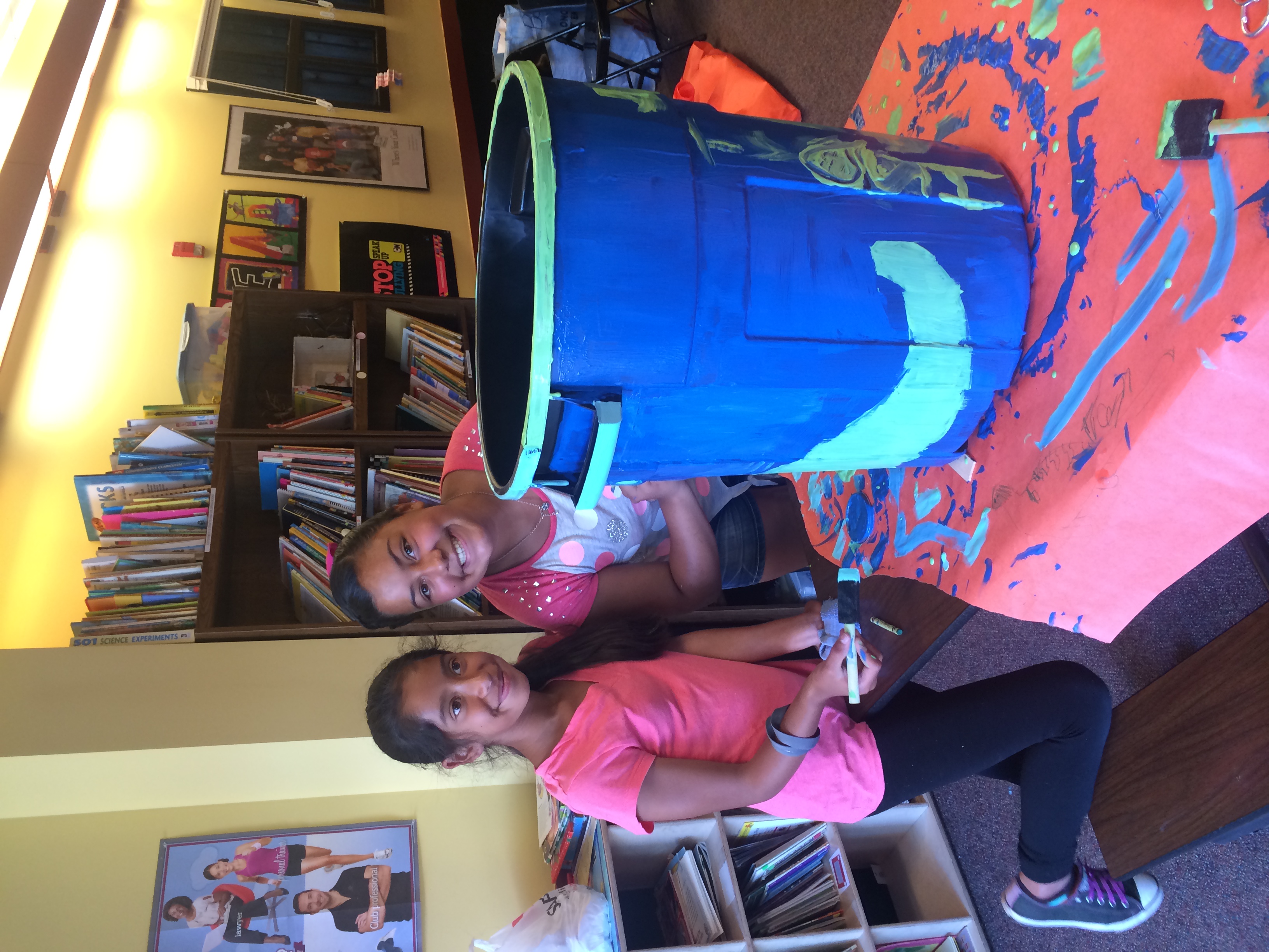 Two club members smile as they finish decorating their recycling bin