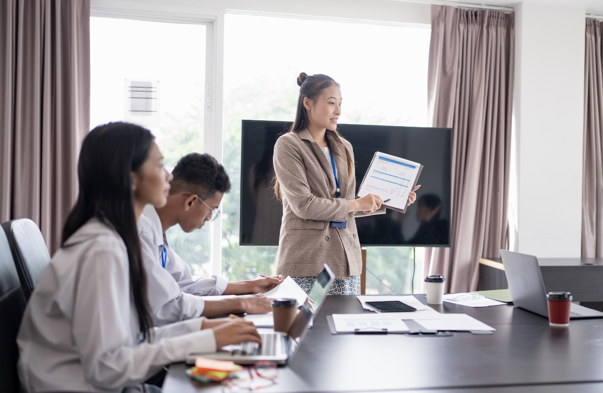Staff sit in an conference room while the team leader shares on-the-job training information.