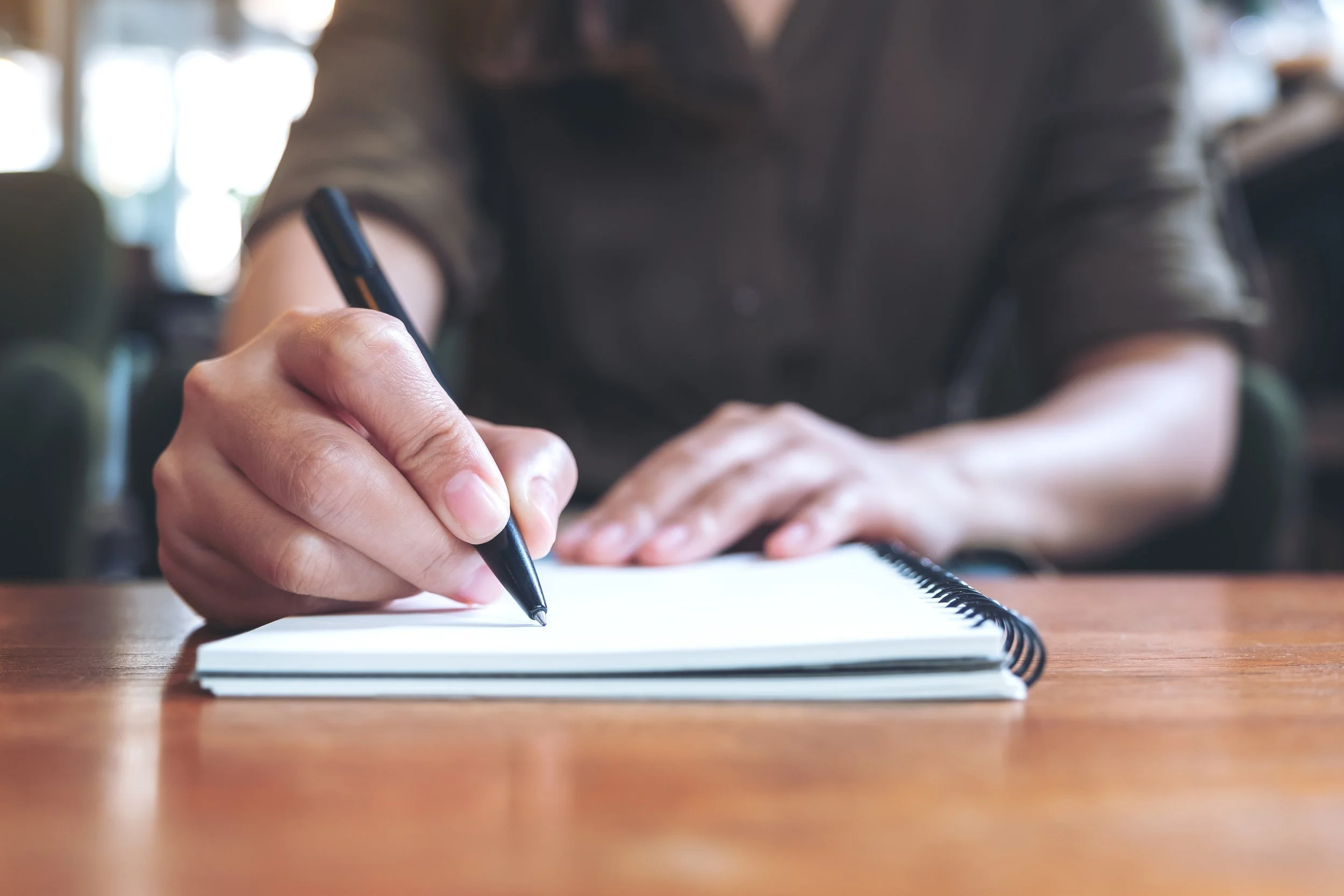 A person takes notes on a notepad.