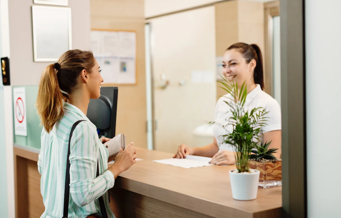 A receptionist greets a patient at a clinic.