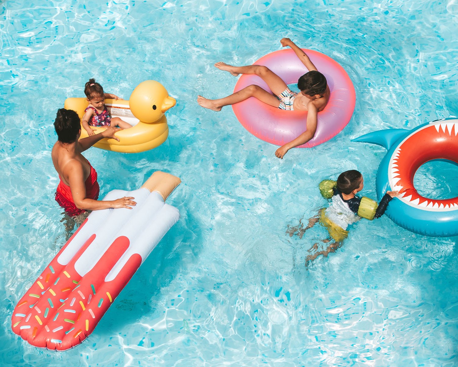 mom-and-kids-playing-in-pool-with-floaties-bright.jpg