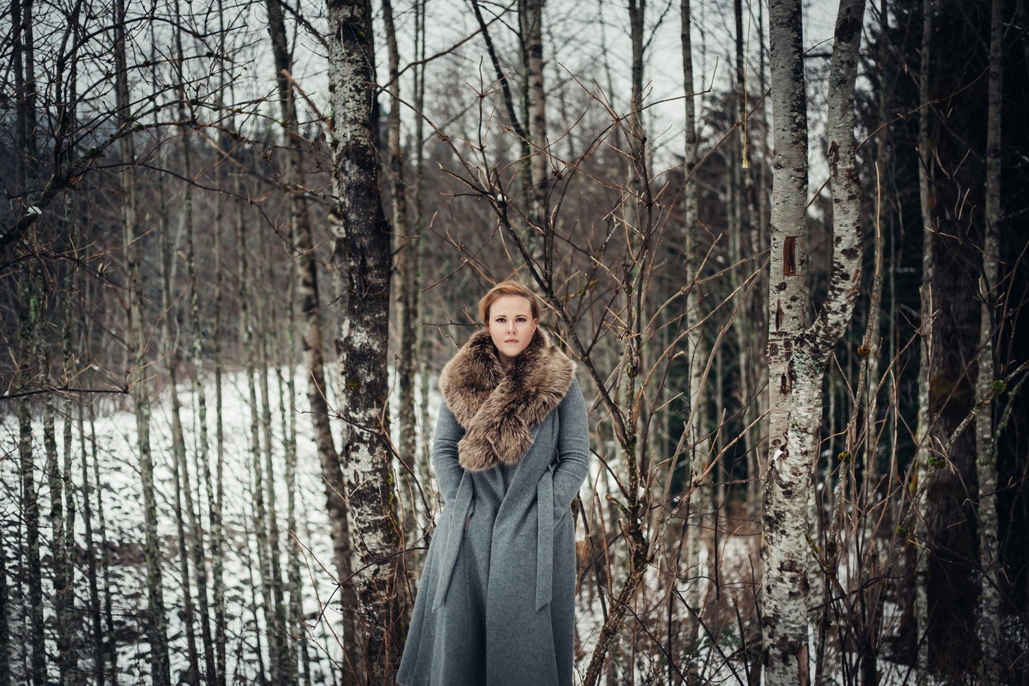 woman-in-coat-standing-in-the-woods-winter-portrait.jpg