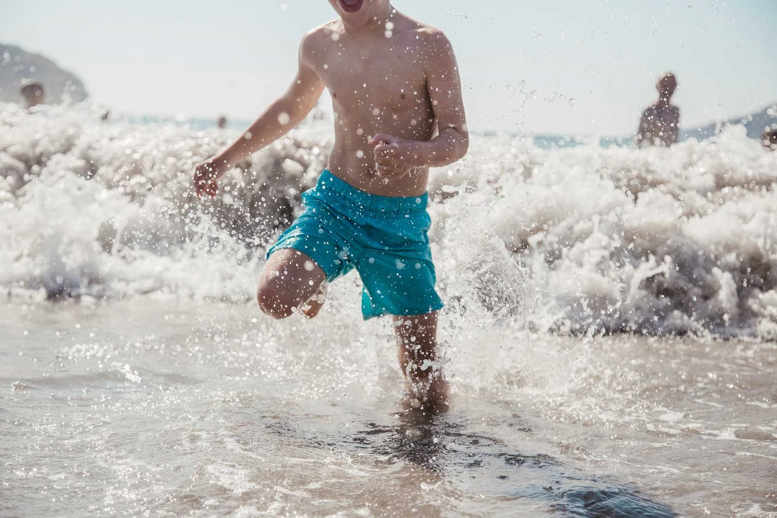adventure-travel-family-photographer-beach-kid-running-through-waves.jpg