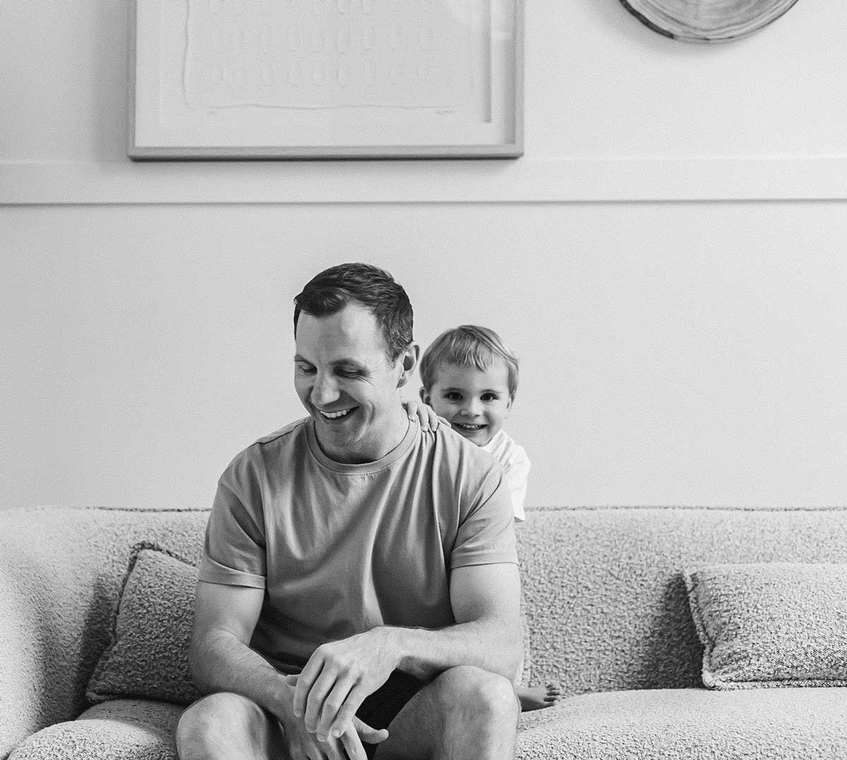 in-home-family-session-dad-son-laughing-on-sofa-lifestyle.jpg
