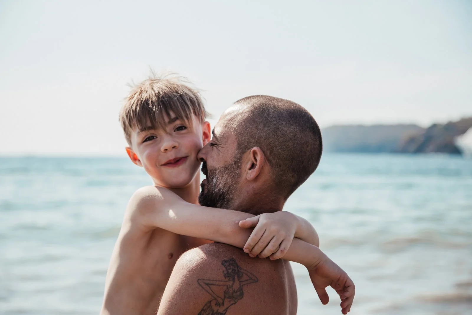 travel-family-photography-dad-and-son-hugging-at-beach.jpg