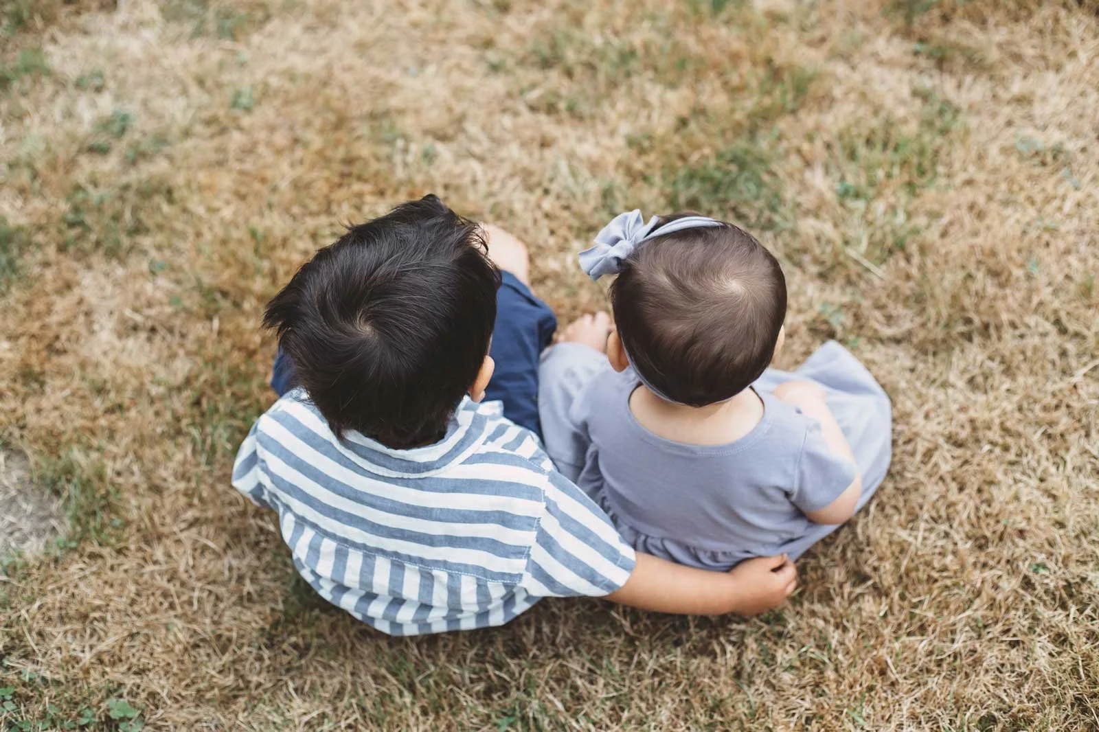 tri-cities-bc-family-photographer-siblings-sitting-in-grass.jpg